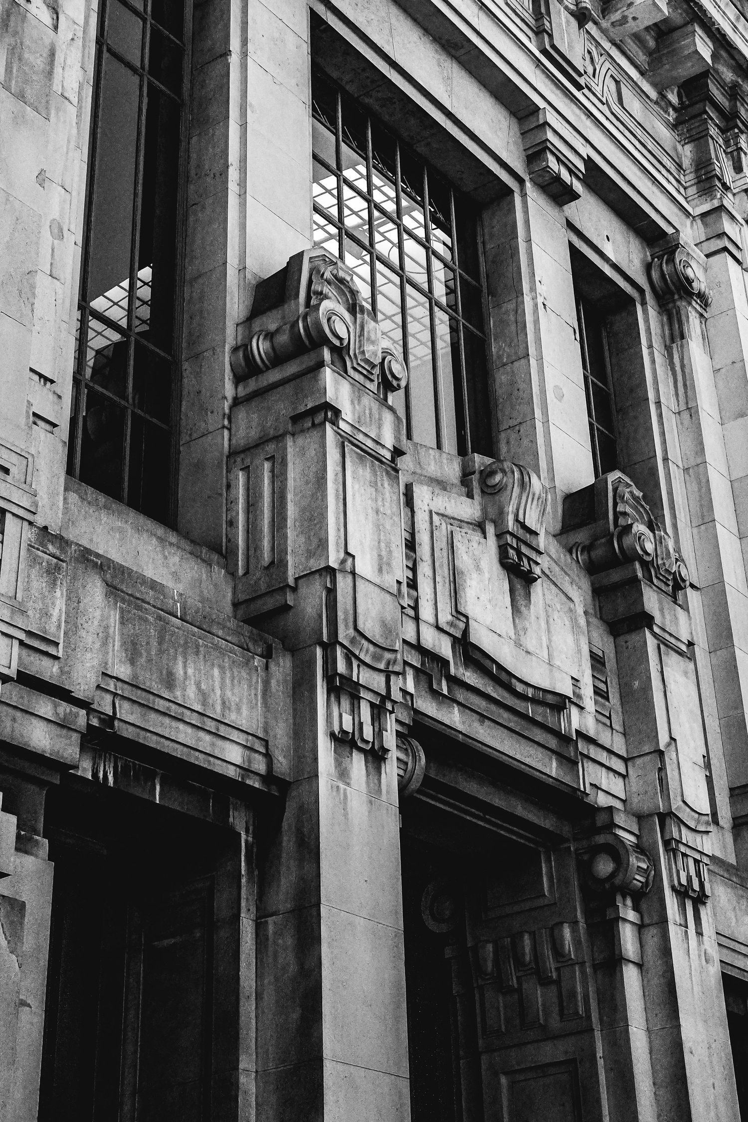 Close-up of ornate architectural details on a classical building facade in black and white.