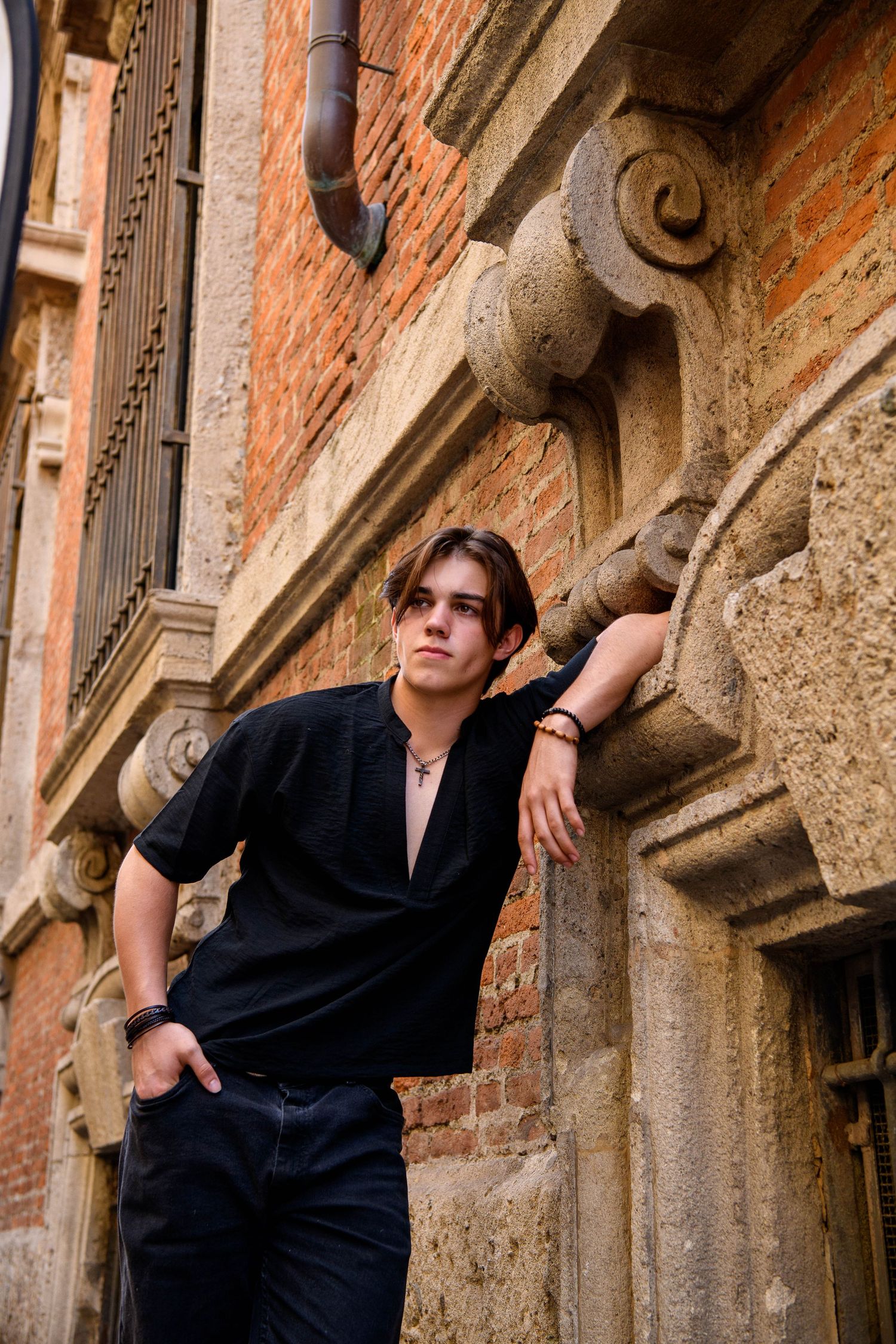 Moody fashion portraits against rustic brick architecture with ornate stone details.