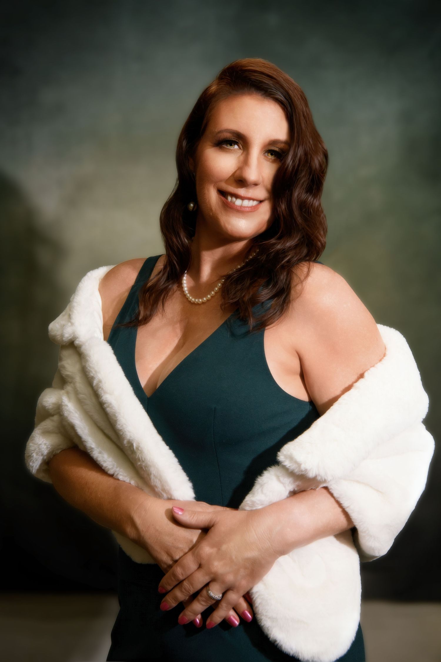 Glamorous studio portrait featuring a dark gown and white fur wrap with classic pearl necklace.