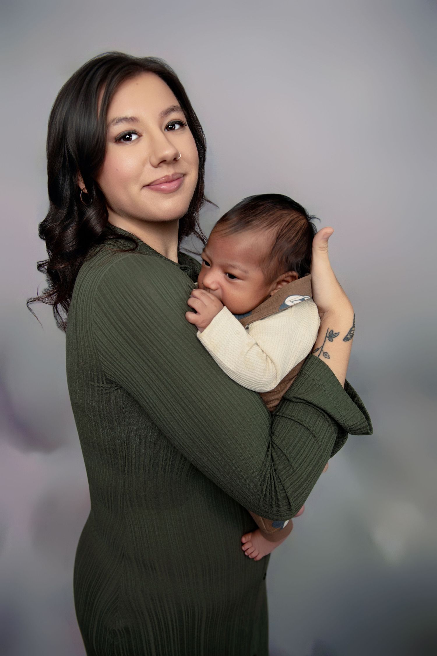 Progressive shots of a mother in an olive green sweater cradling and bonding with her infant.