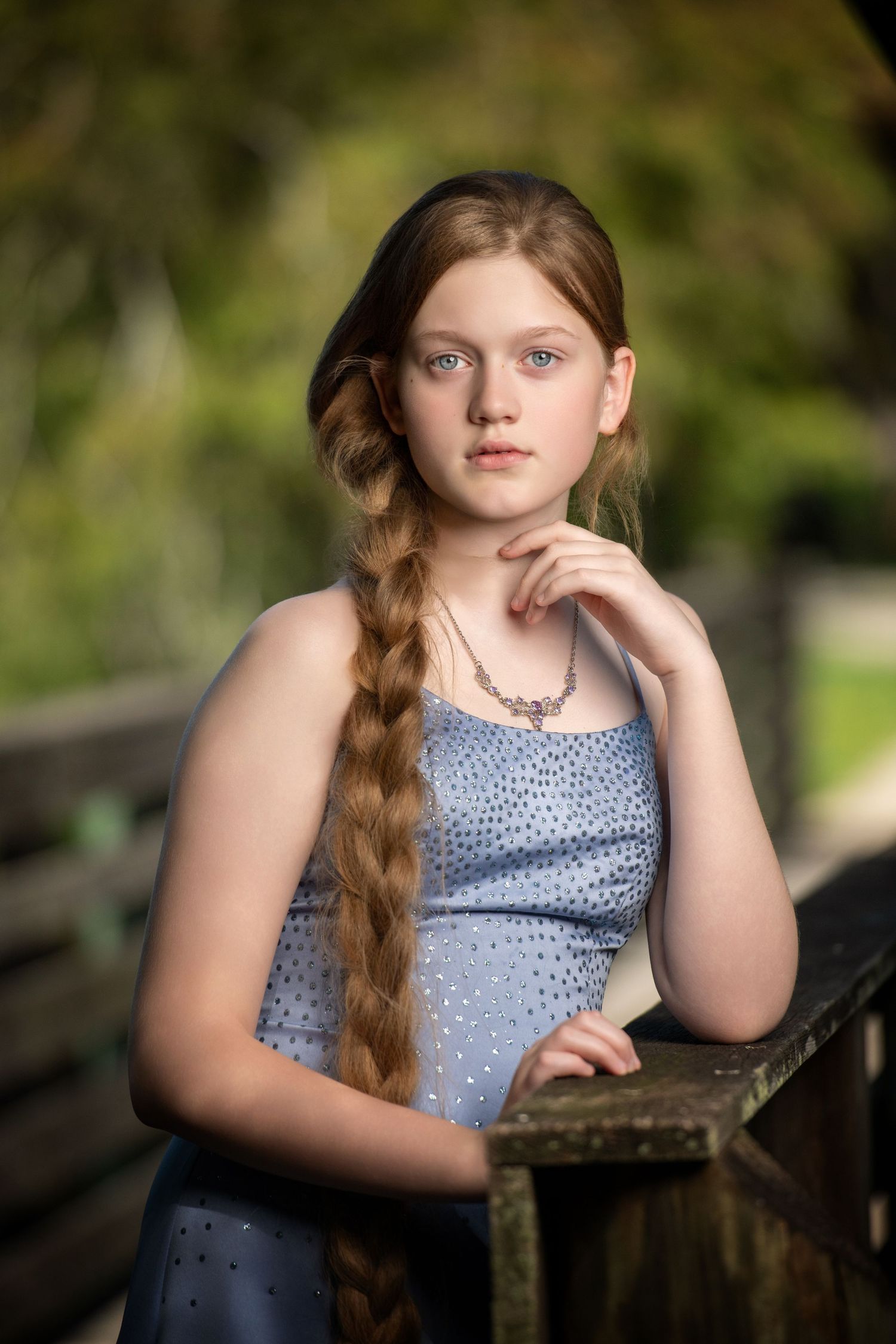 Outdoor portrait series in a blue polka dot dress near a wooden fence.