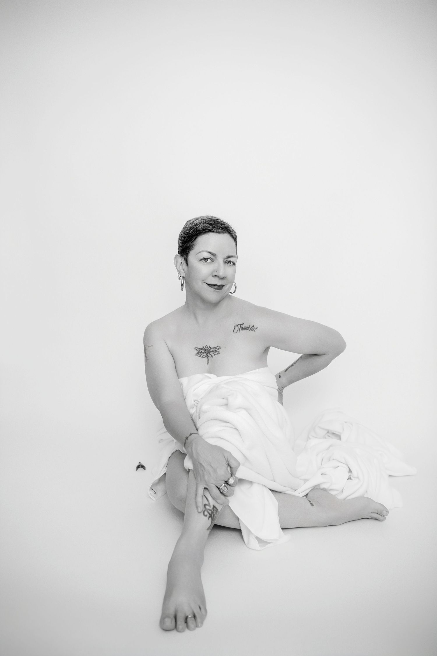 Black and white artistic portrait of a figure draped in white fabric against a minimalist background.
