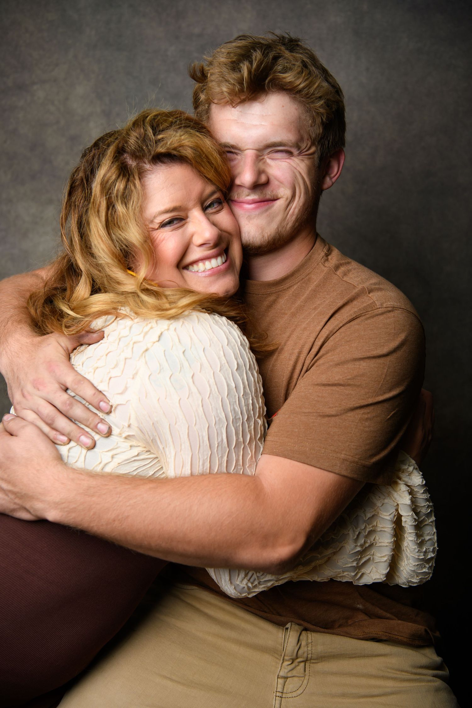 A couple sharing intimate embraces and laughter against a dark studio background.