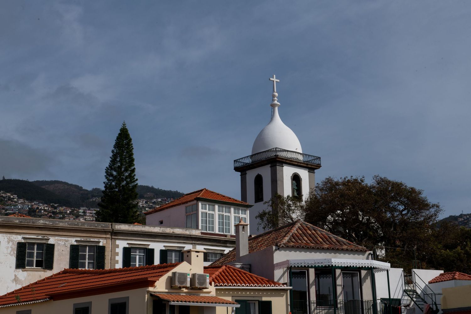 Historic church buildings and architecture in Funchal's old town with domed structures.