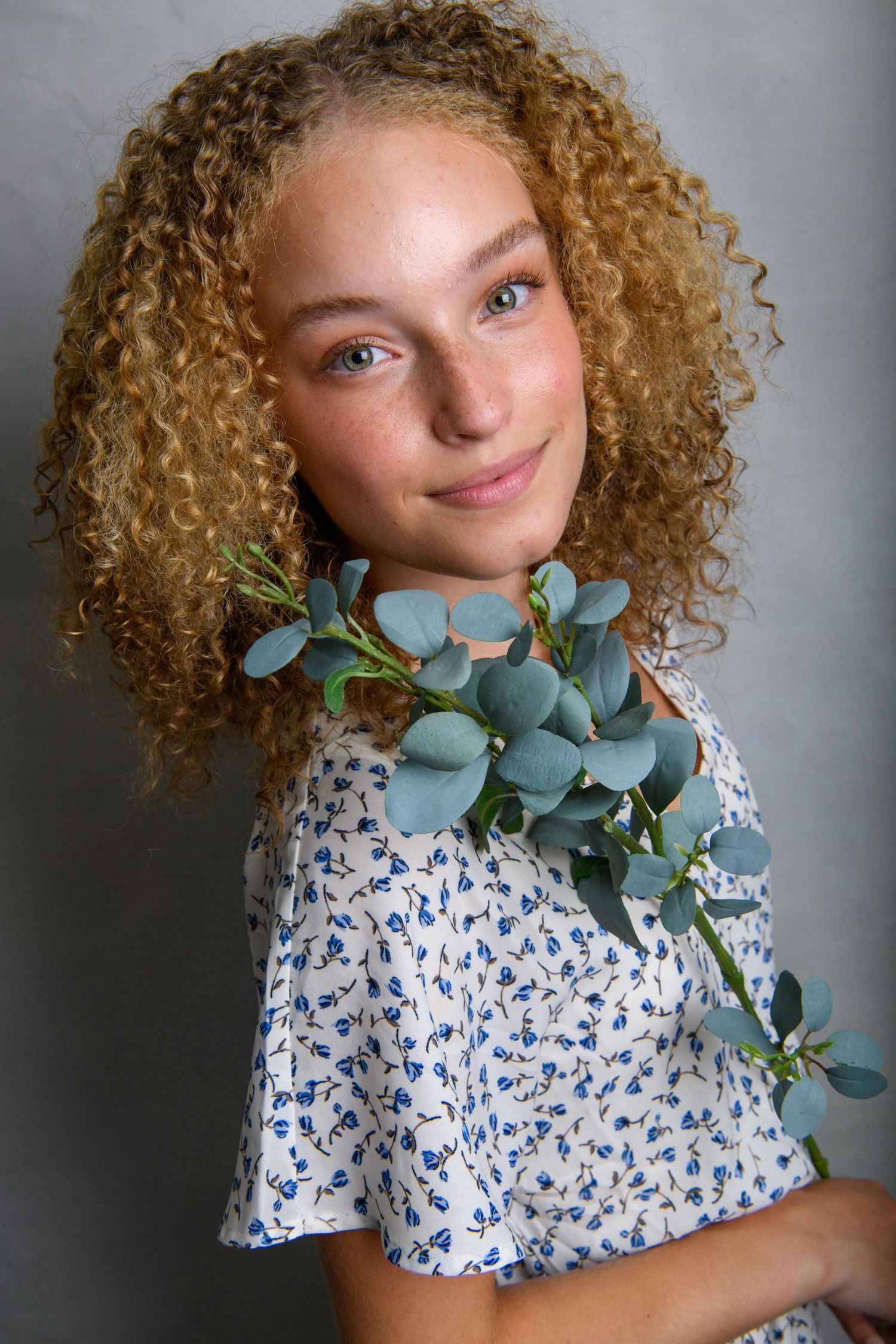 Studio portrait with eucalyptus branch wearing delicate blue and white floral dress.