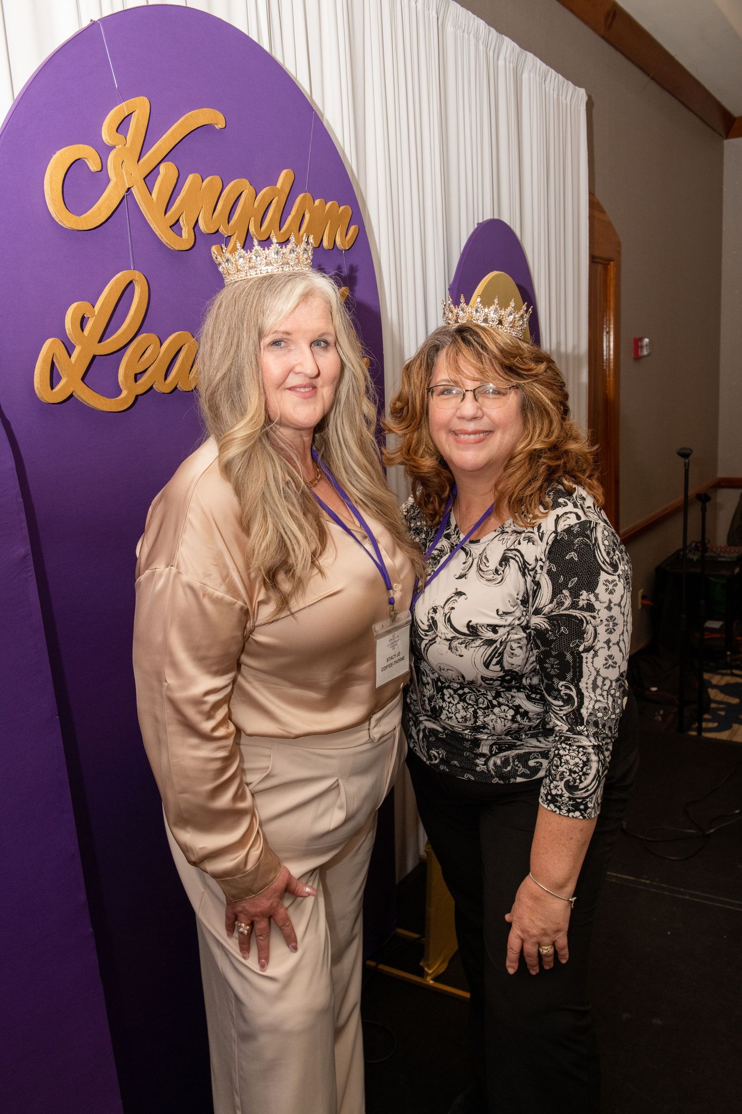 Two attendees standing in front of purple Kingdom Leader backdrop at formal event of the Association of Christian Business Women, Palm Beach