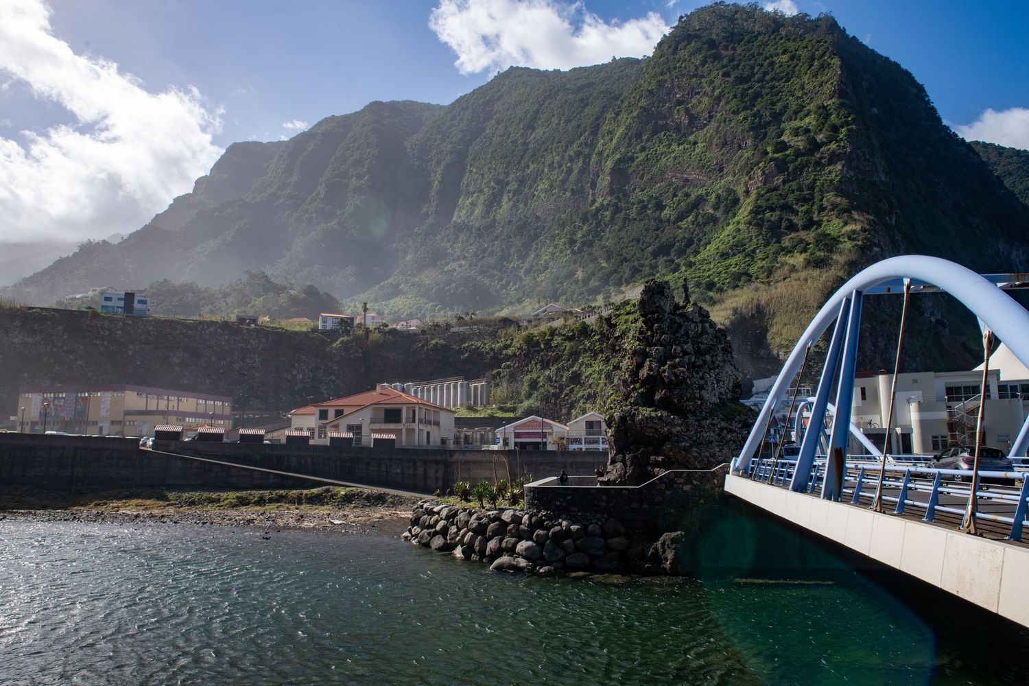 Scenic harbor view with white bridge and mountains creating a dramatic coastal landscape.