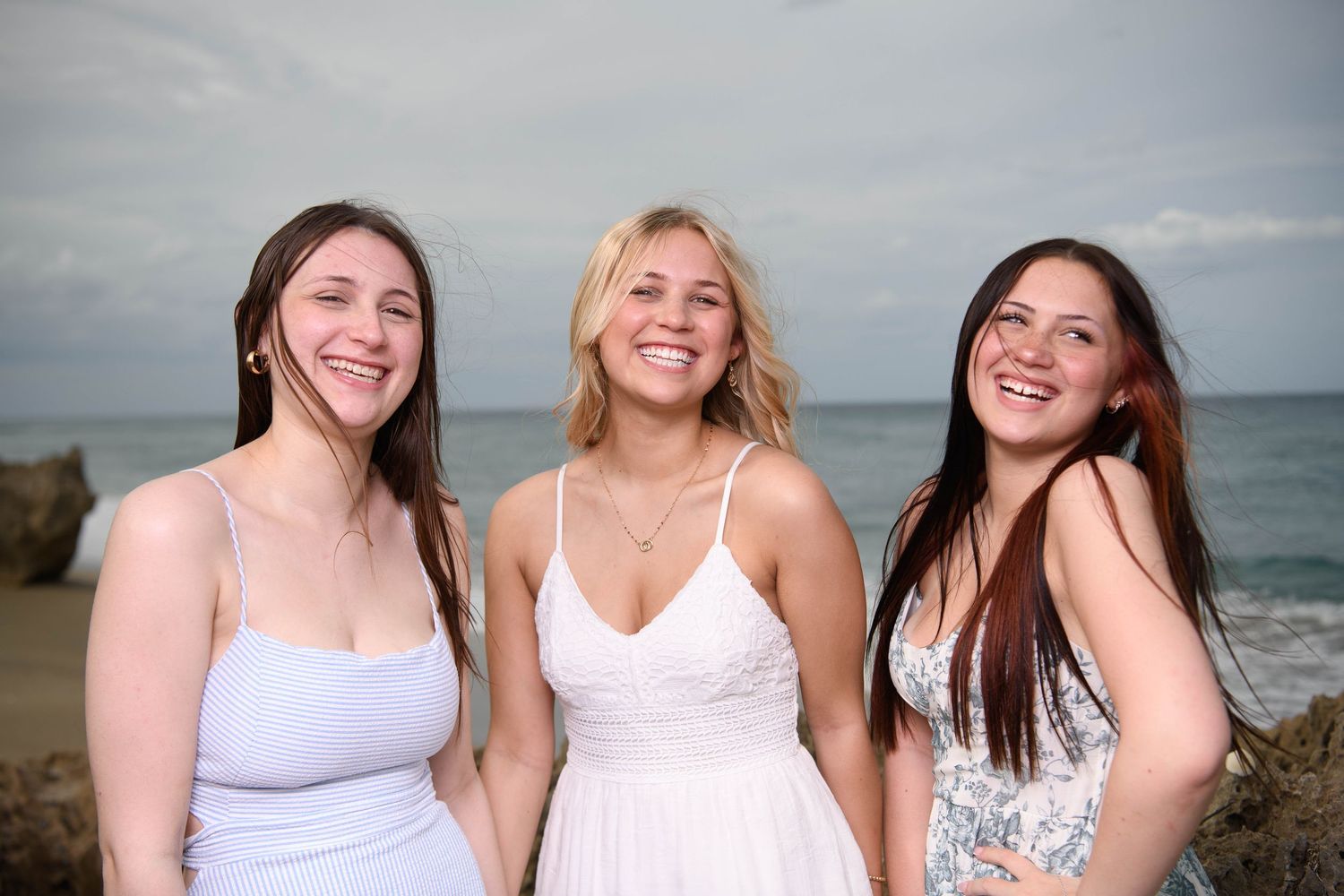 Group of friends laughing and enjoying time together at the beach on a cloudy day.