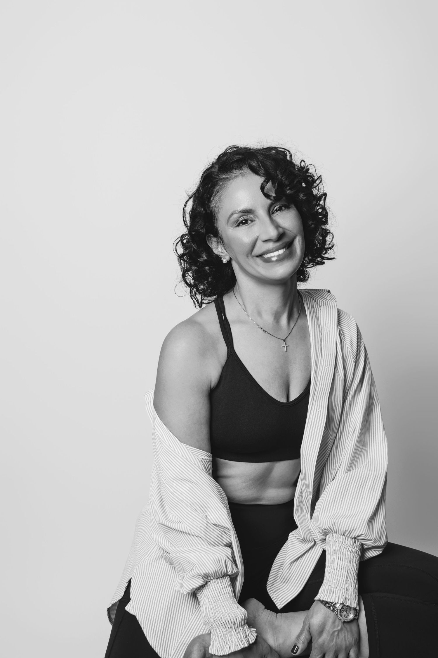 Studio portrait showing natural curly hair and casual athletic style against white background.
