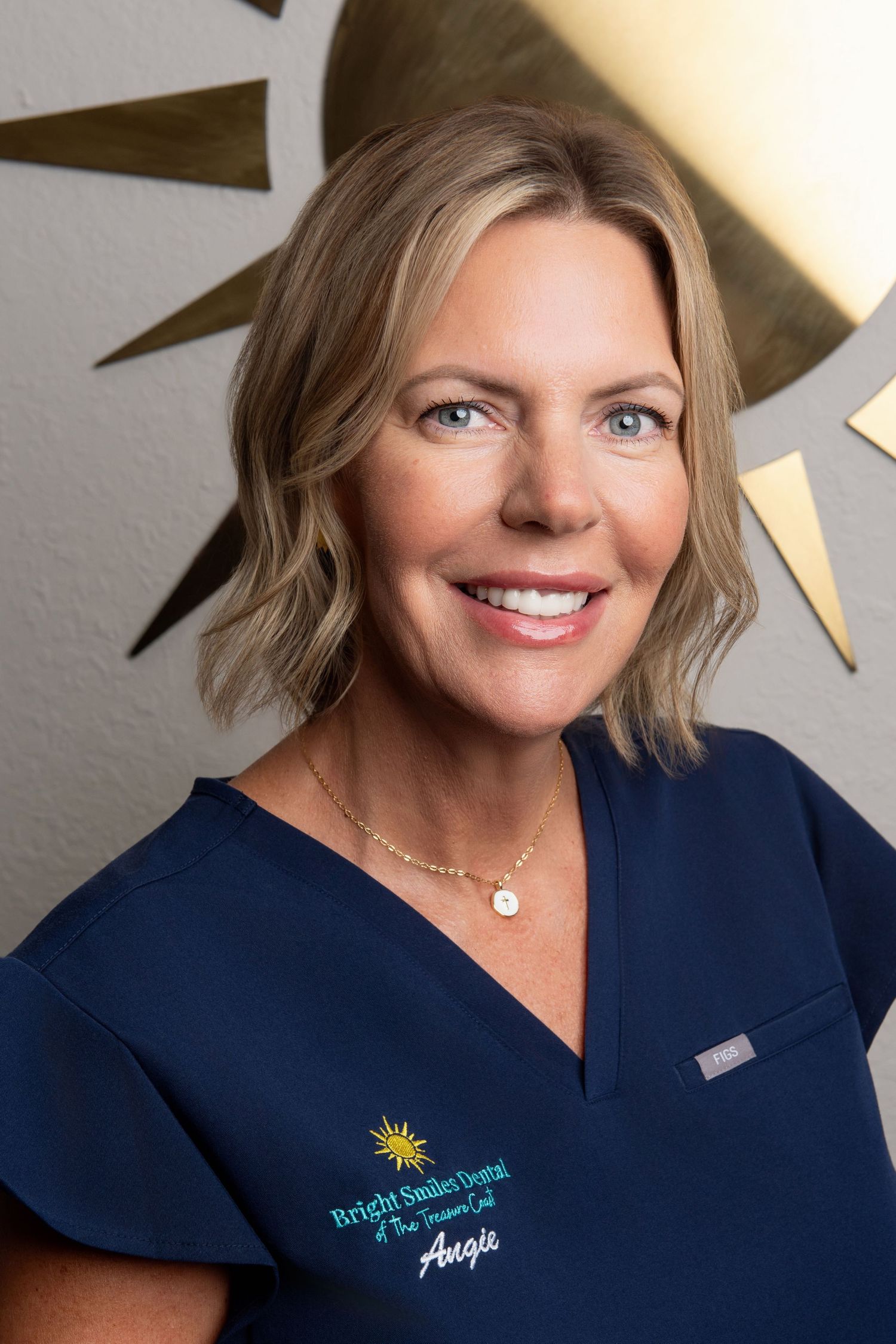 Staff member in navy medical uniform smiles during professional portrait session.