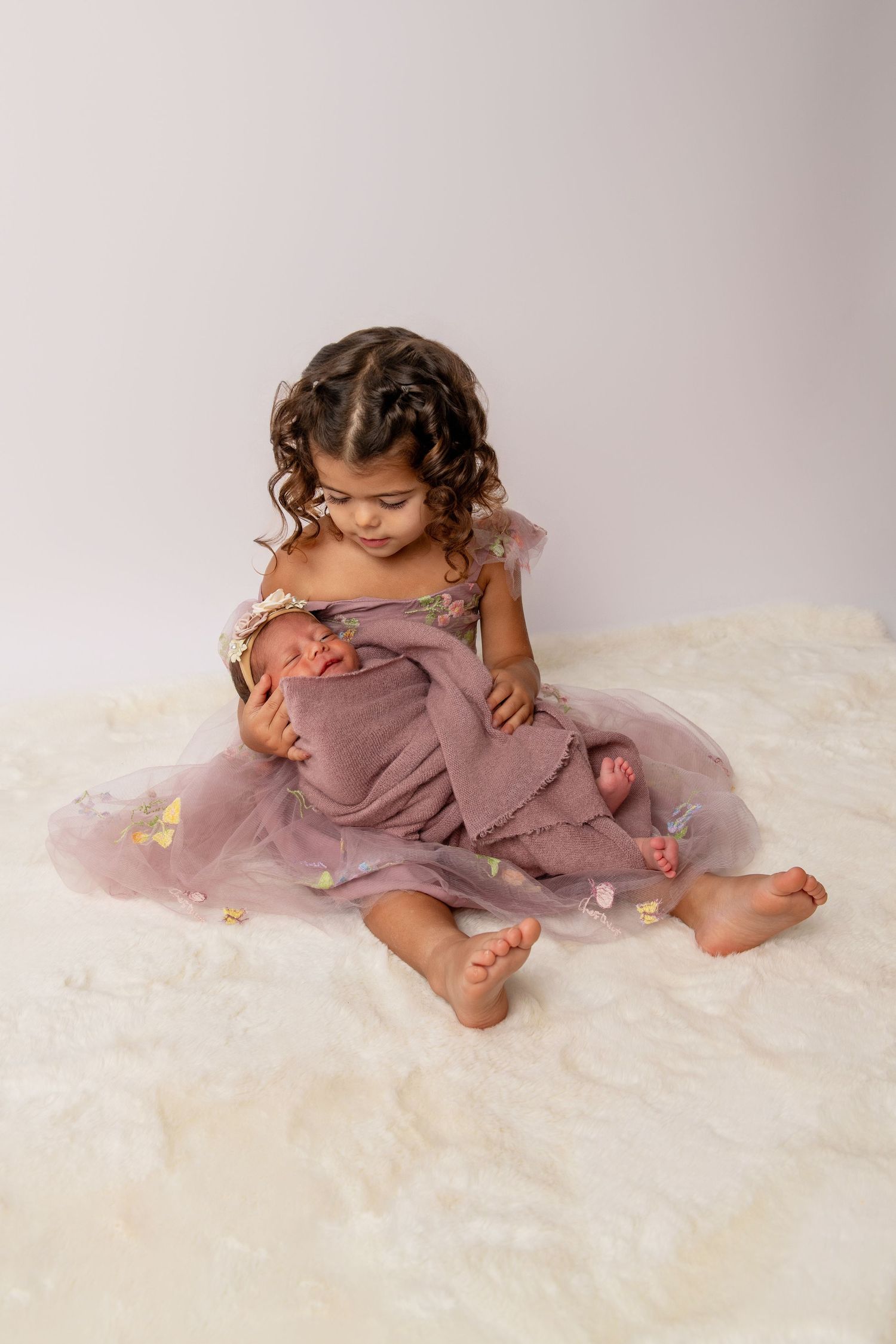 Baby in purple onesie lying on soft white blanket in series of artistic poses.