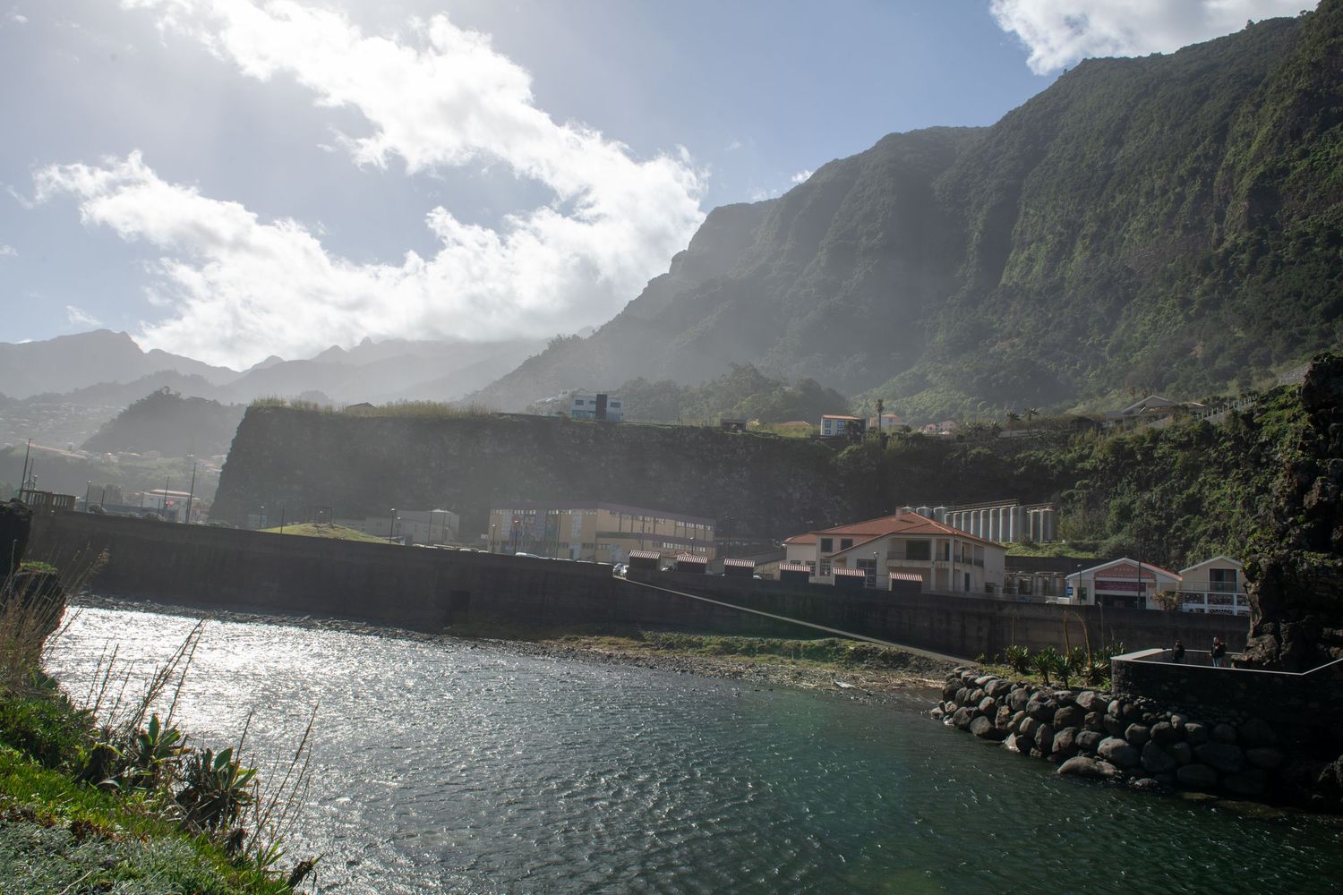 Panoramic view of a coastal town nestled between dramatic mountains and ocean waters.
