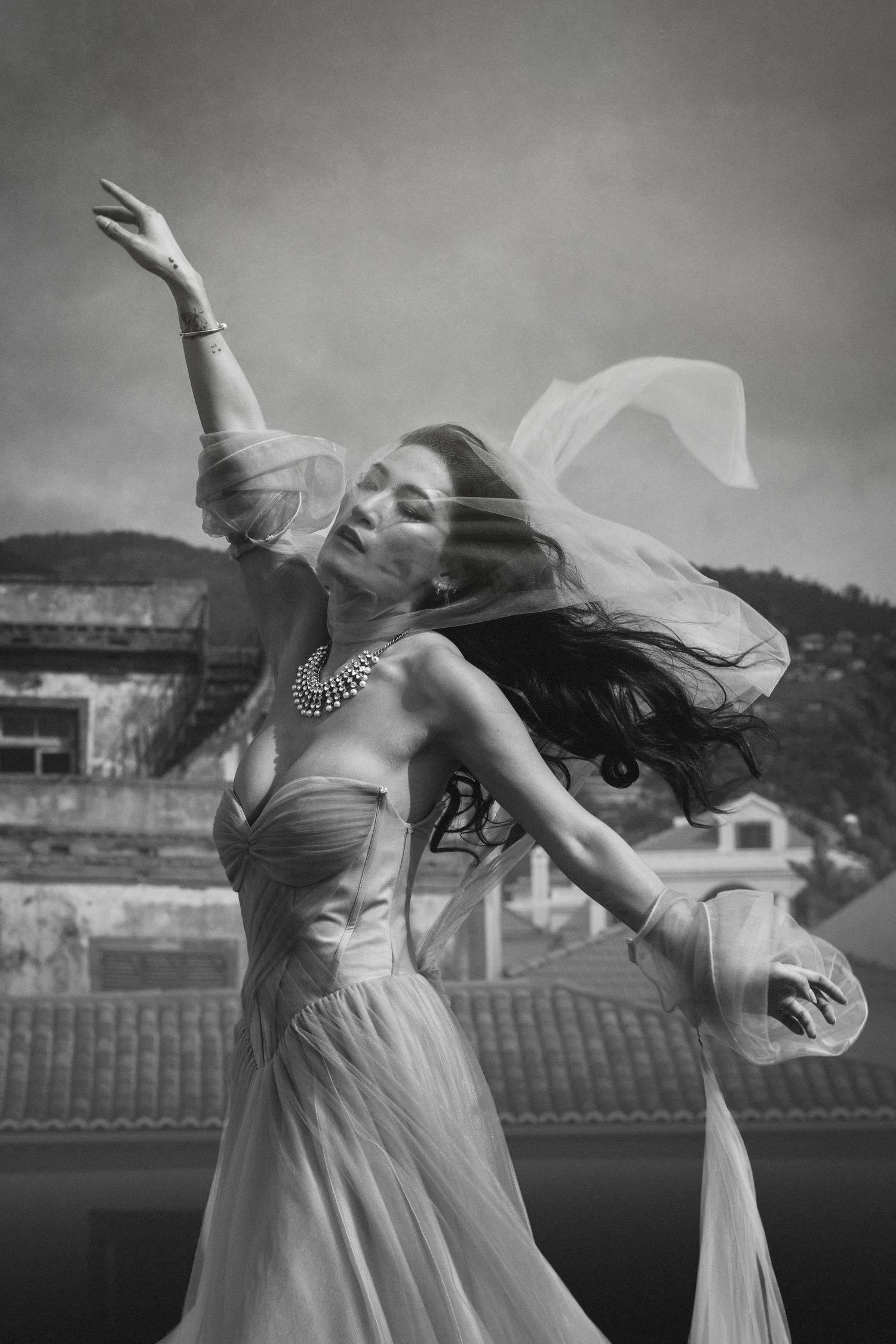 Graceful dance pose captured in black and white with floating fabric and elegant jewelry.