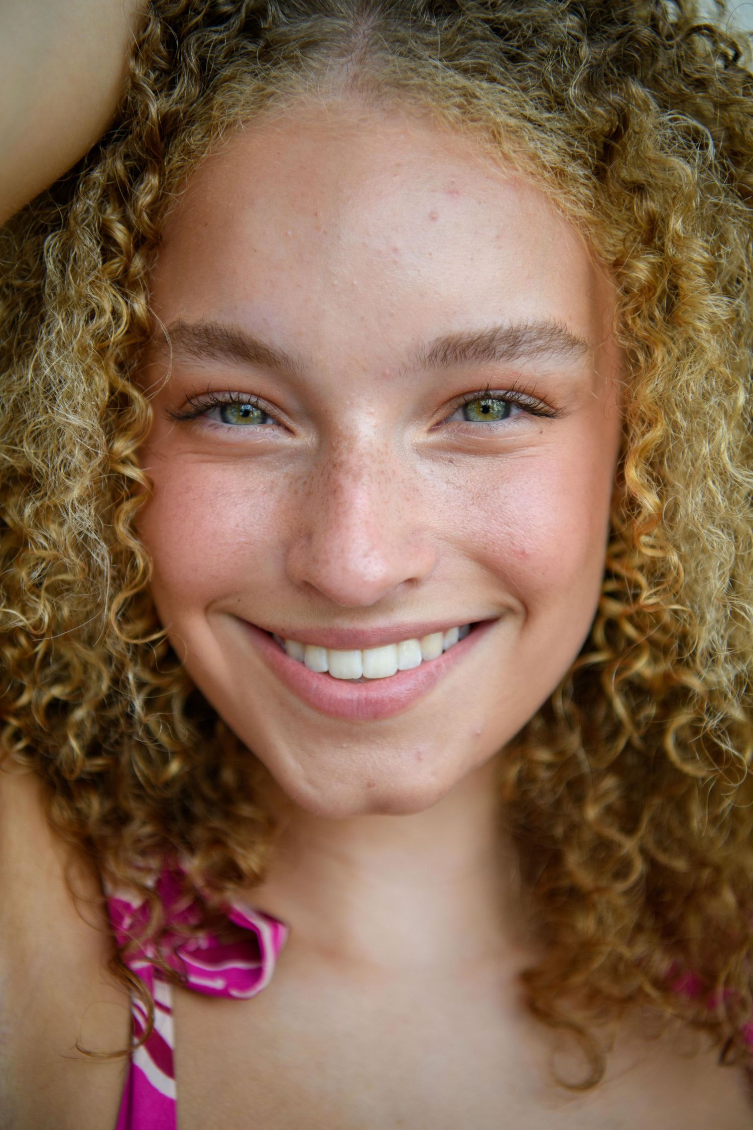 Close up portrait showing natural curls and bright smile.