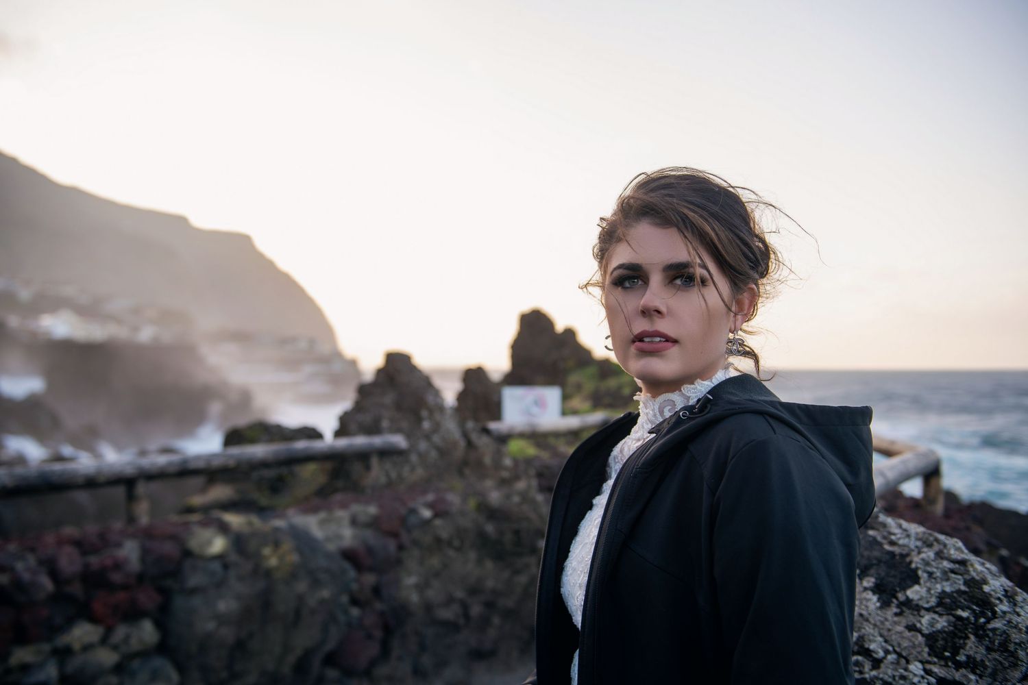 Moody coastal portrait with dramatic cliffs and ocean waves in background.