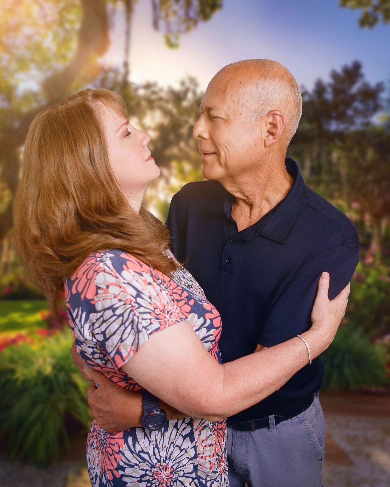 Romantic senior couple embracing outdoors in a garden setting during golden hour.