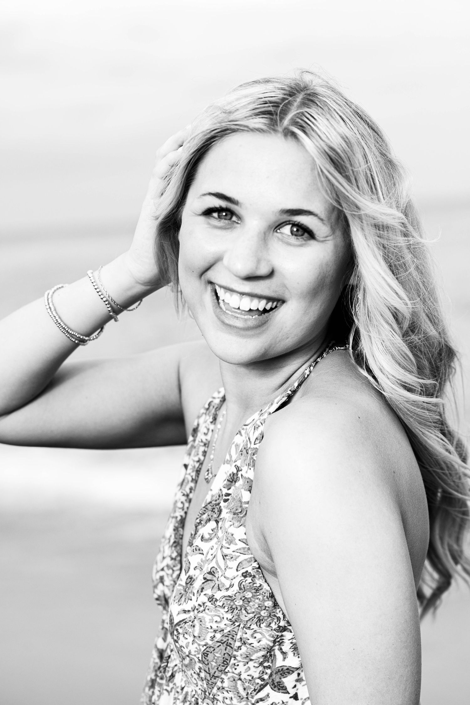Black and white portrait with bright smile and flowing blonde hair.