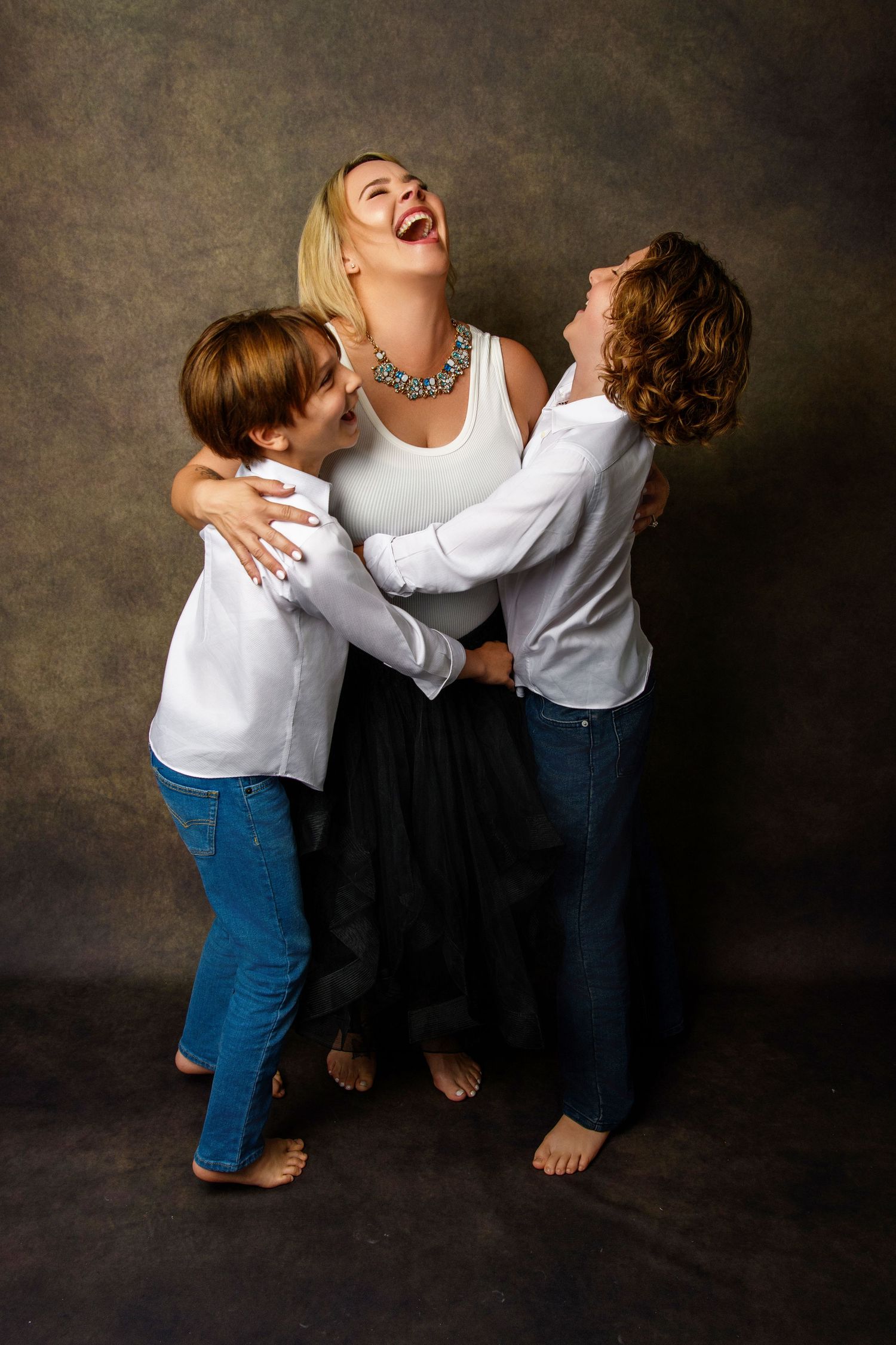 Candid black and white studio portraits capturing joyful family moments against a dark background.