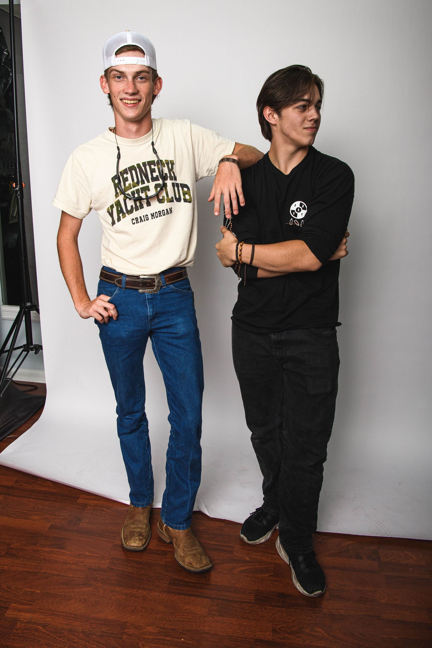 Two people in contrasting outfits pose together against a white studio backdrop.