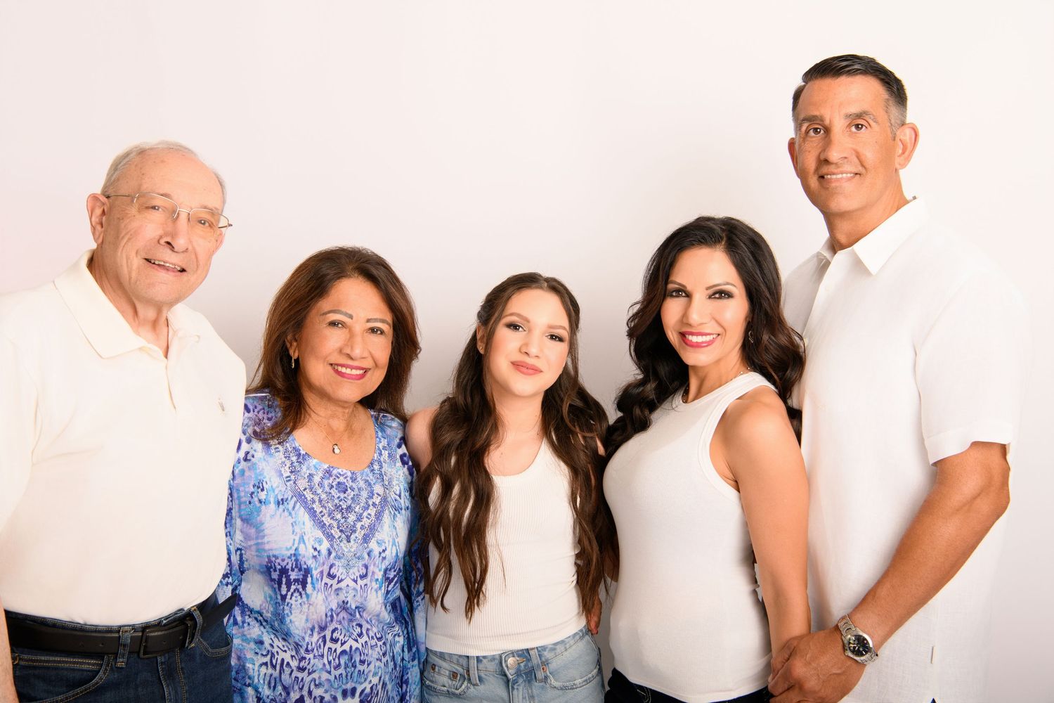 A multi-generational family poses together for studio portraits in coordinated outfits.