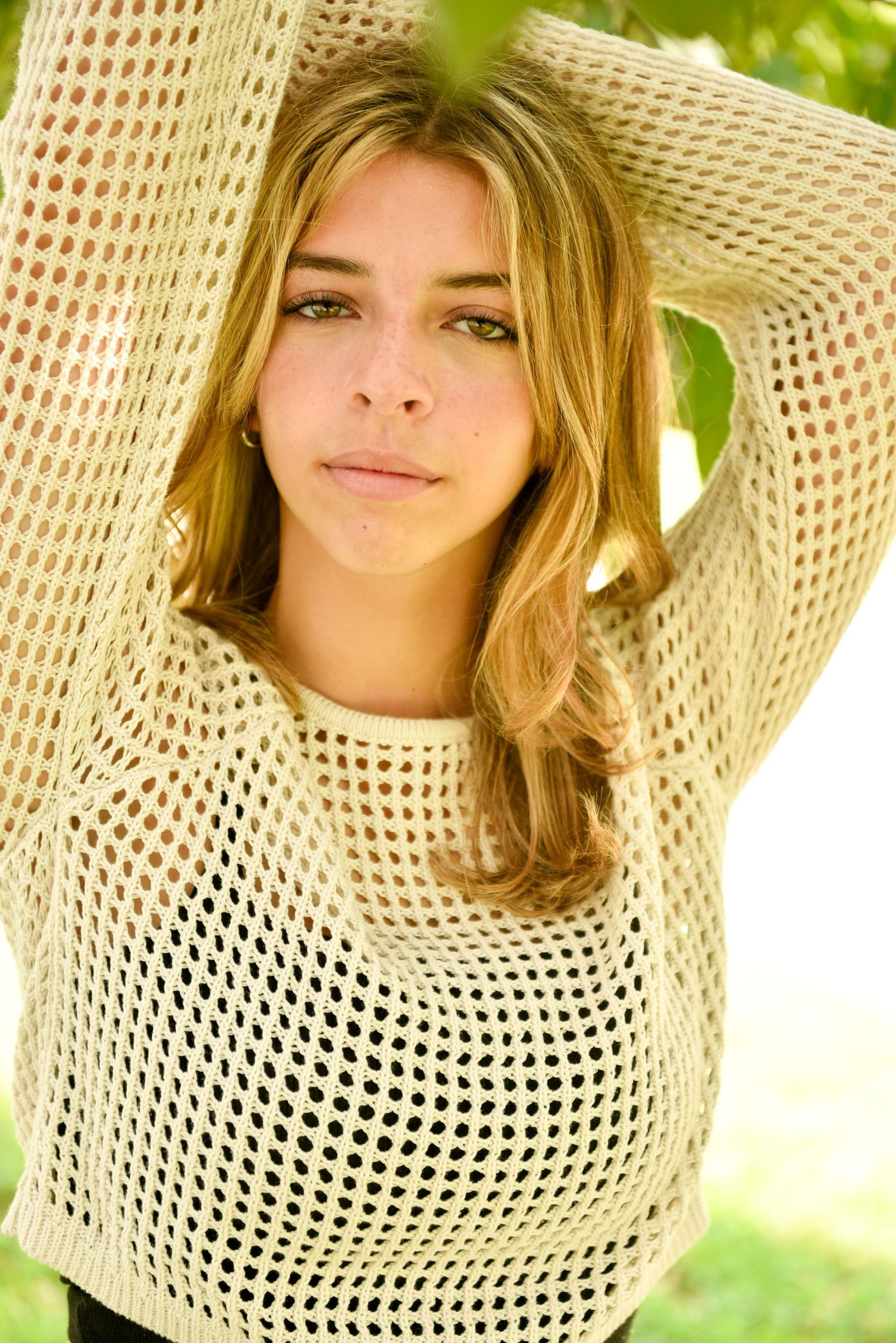 Close-up series in a cream crochet sweater with natural outdoor lighting and greenery.