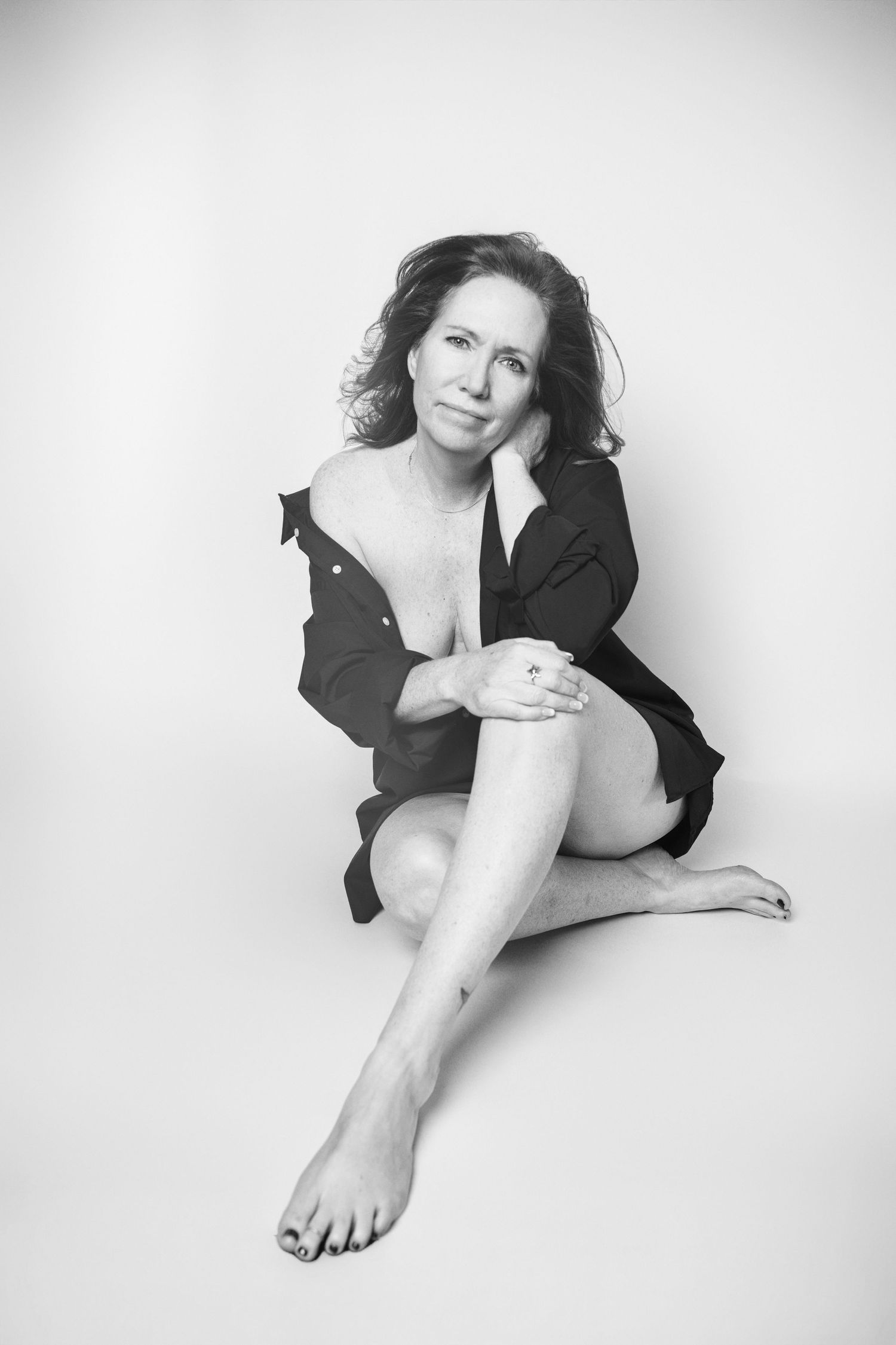 Artistic black and white photos of a person in dark clothing posing on floor.