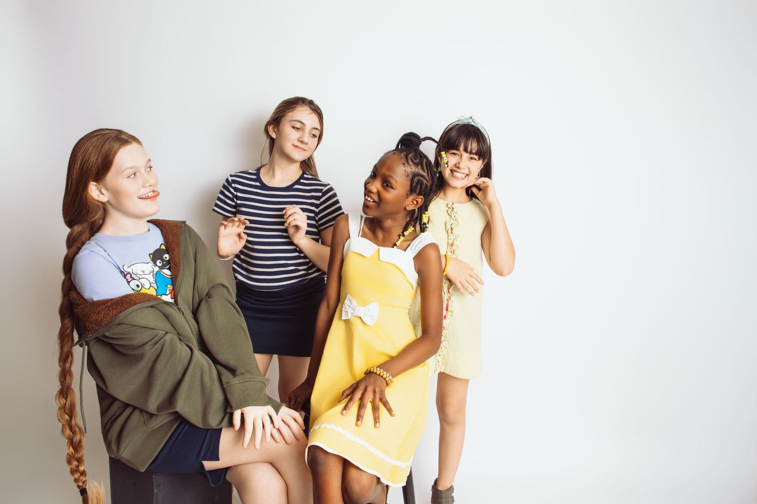 A group of friends posing together in casual outfits against a white background.