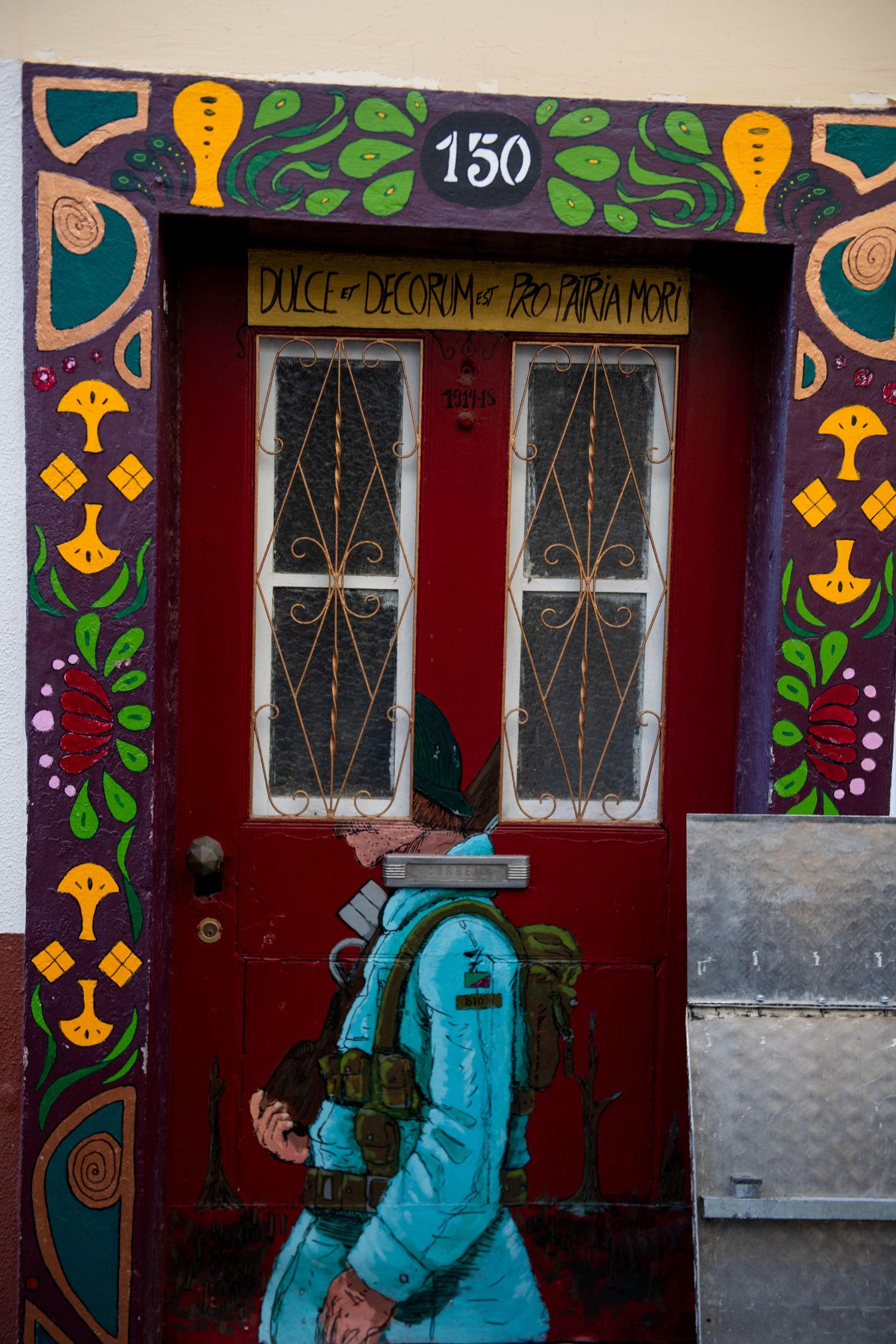 Colorful painted doorway with decorative folk art patterns and turquoise details on red background.