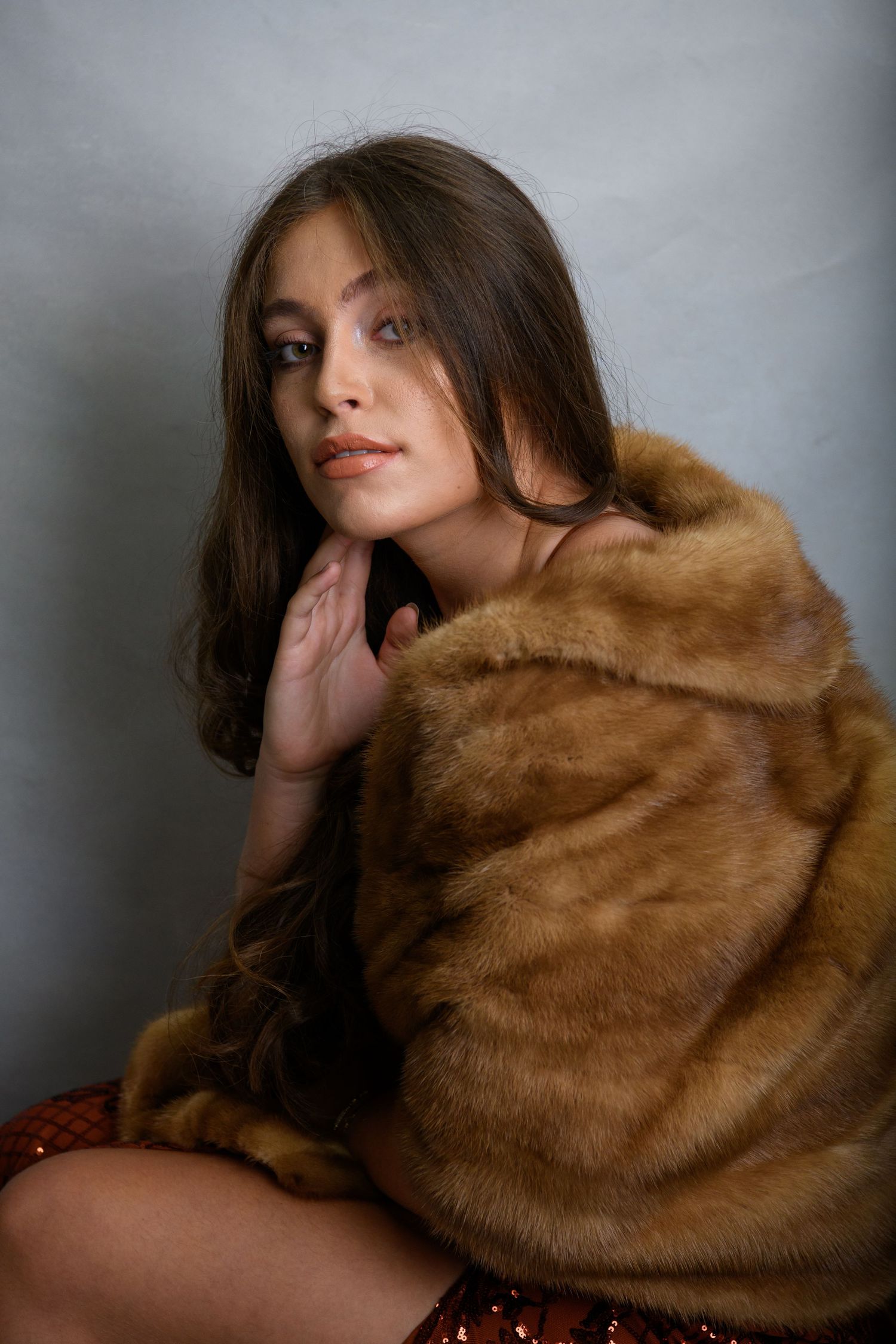 Glamour shots with a luxurious brown fur wrap creating dramatic poses against a gray backdrop.