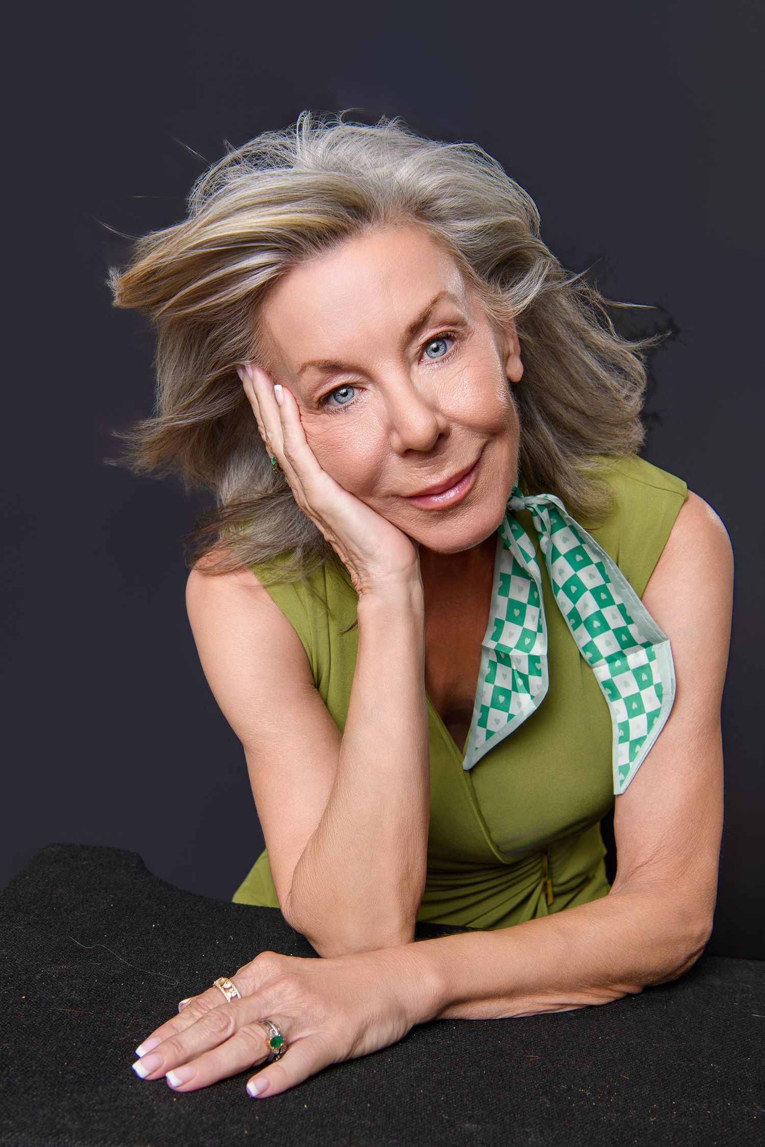 Artistic photo series of someone posing on black fabric in a green sleeveless top.