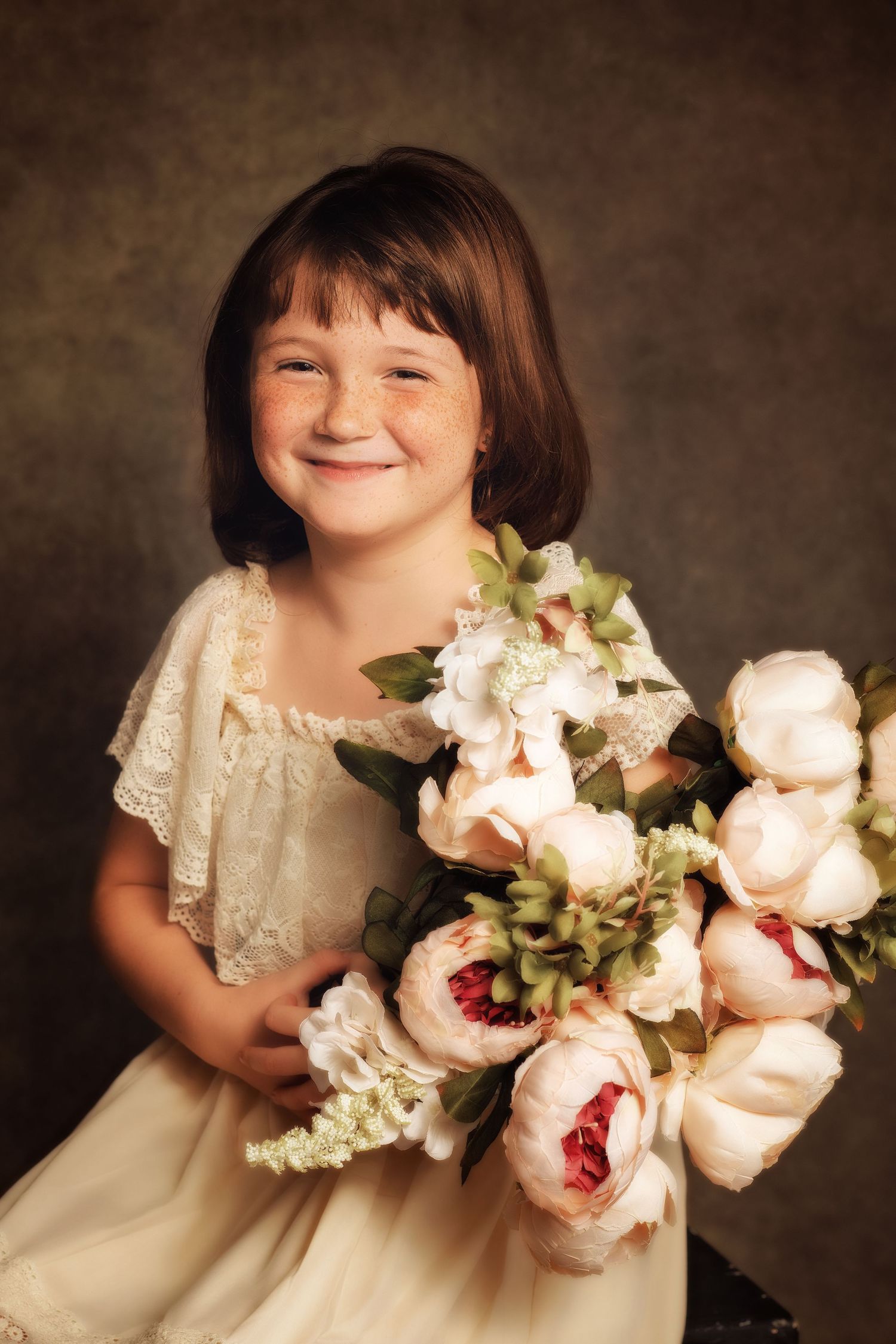 Child in vintage lace dress holding beautiful bouquet of pale pink roses.