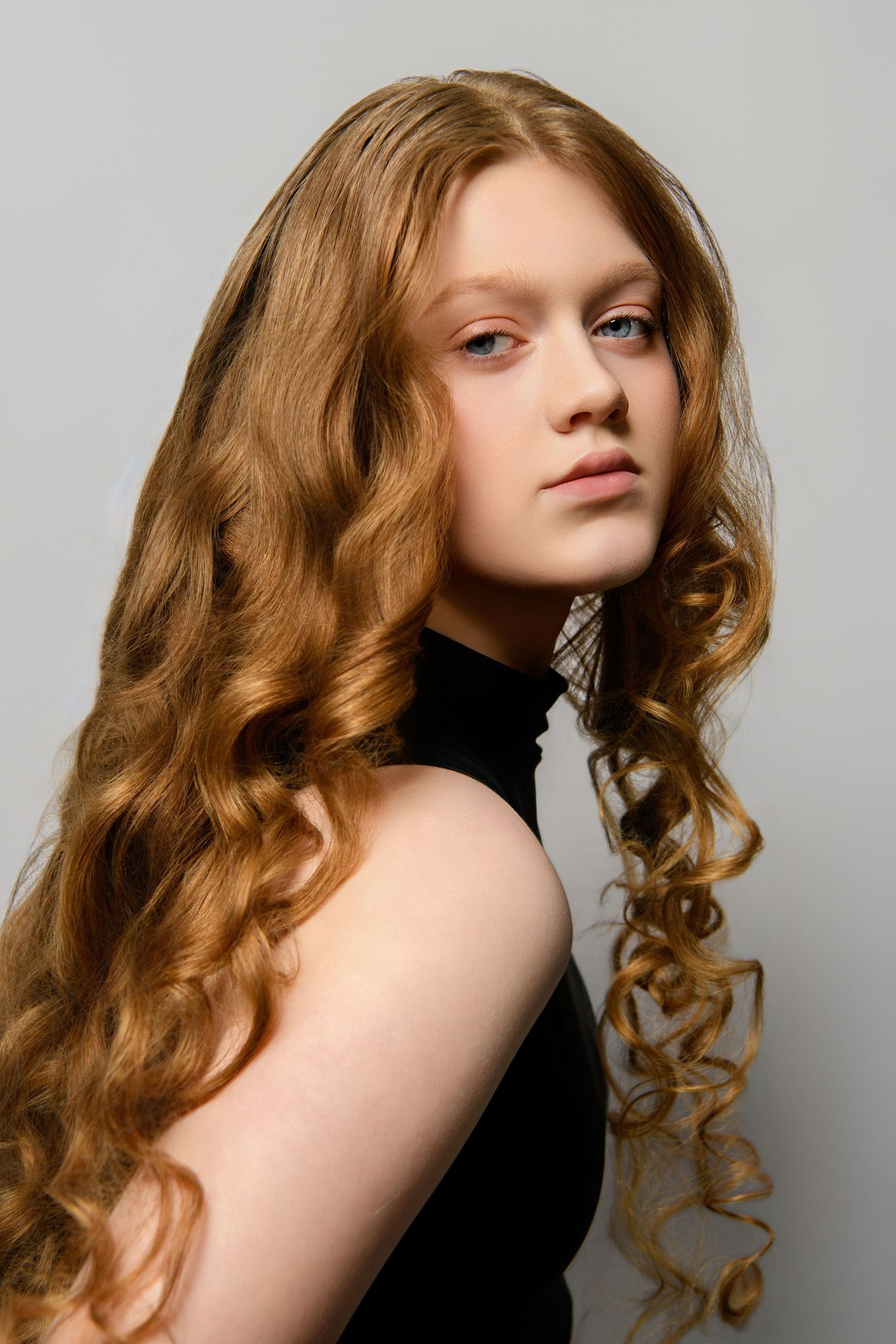 A series of fashion portraits showing curly red hair and a black turtleneck against a light gray background.