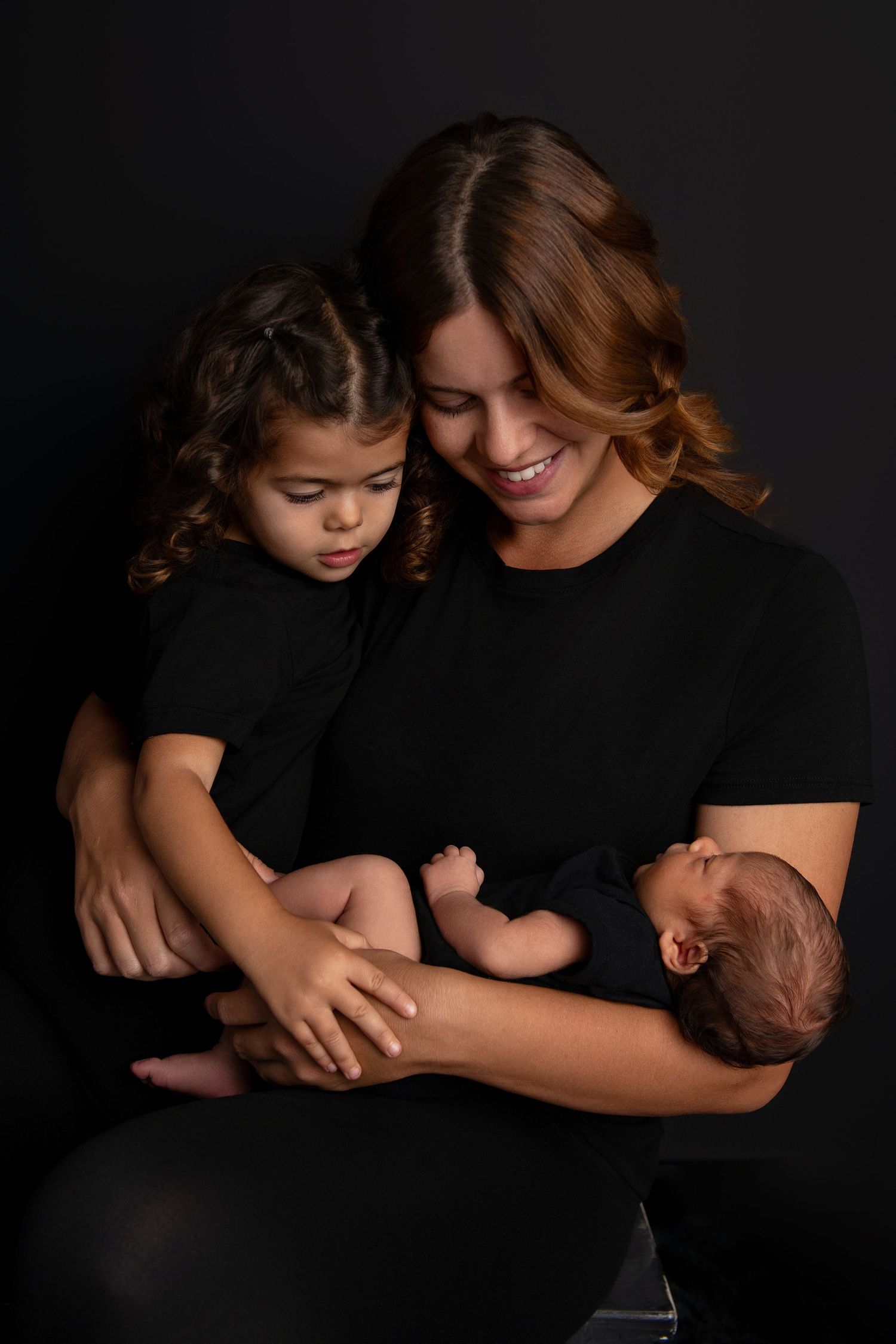 Intimate family portrait series with newborn baby in dark moody lighting.