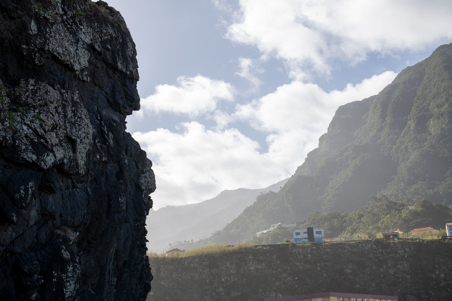 Rugged mountain landscape meets the ocean under bright blue skies.