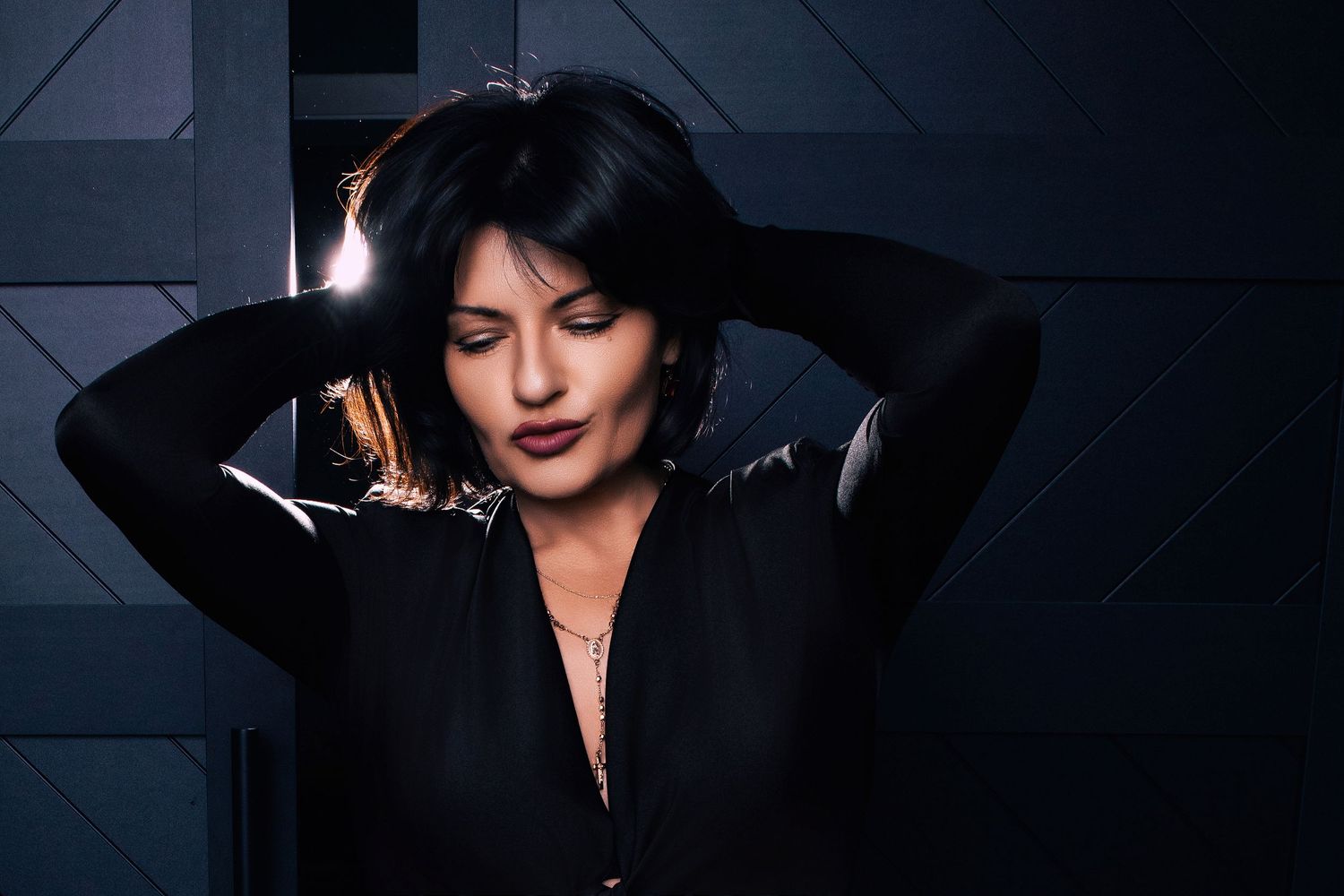 Moody portrait series in dark setting with dramatic lighting and geometric background.