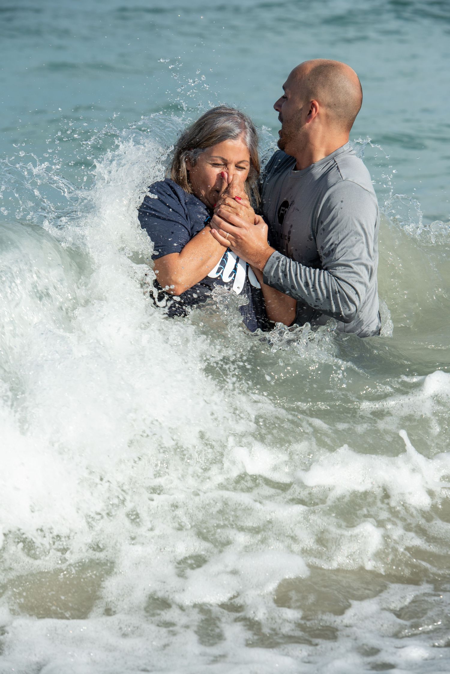 Pastor Stephen Rice of family church Jensen Beach baptizes local woman in ocean on Jensen beach,  dramatic water splashing around them.