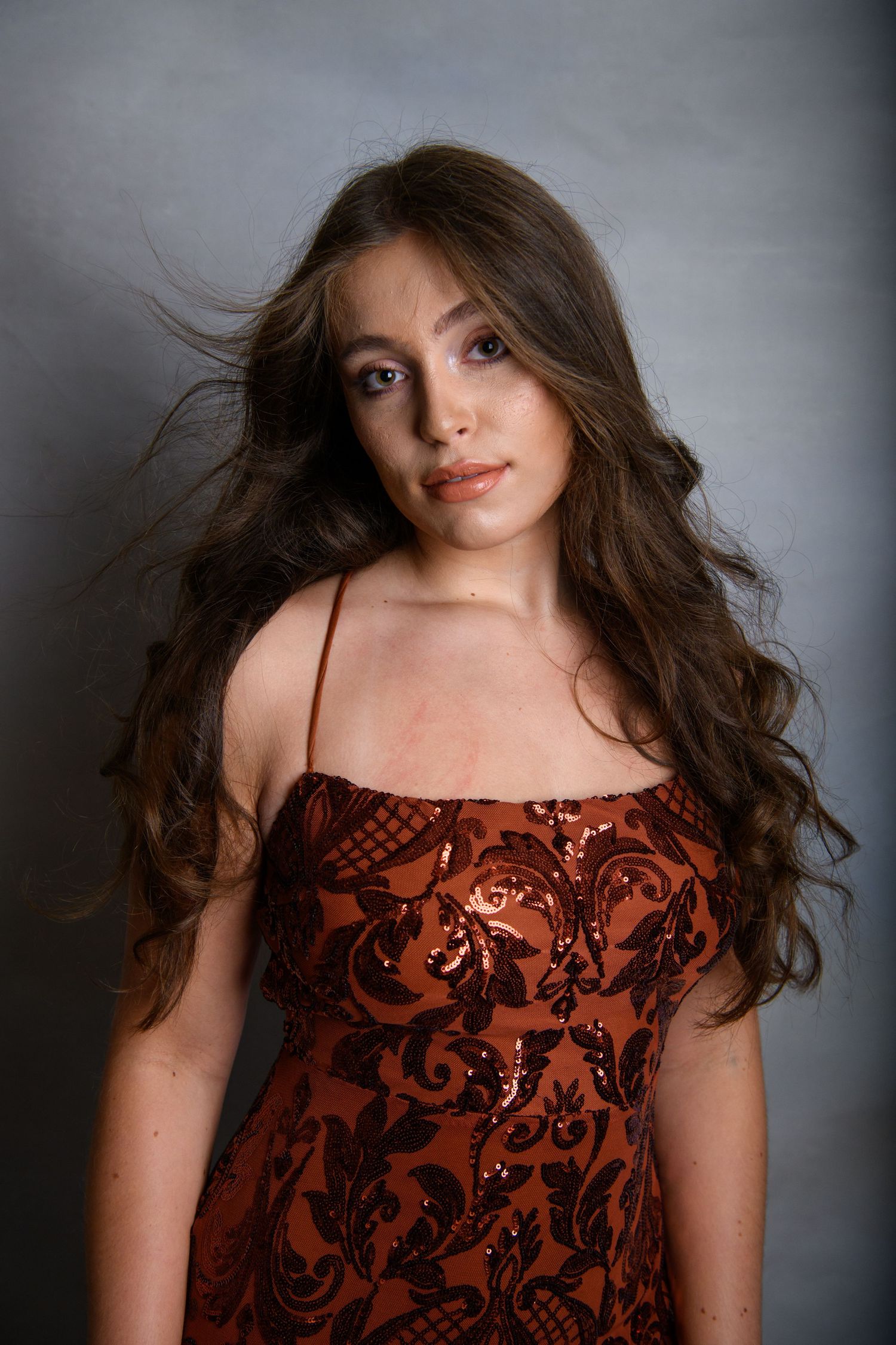 Sequence of fashion portraits showing movement in a burgundy patterned dress against a dark background.