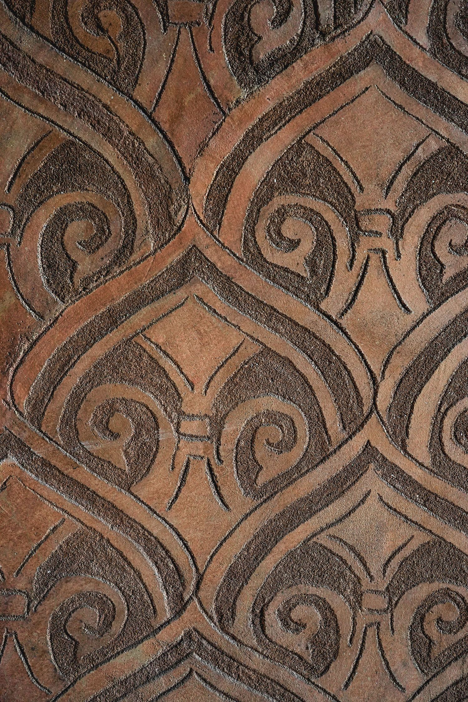 Detailed brown textured pattern with intricate swirling designs and geometric shapes.