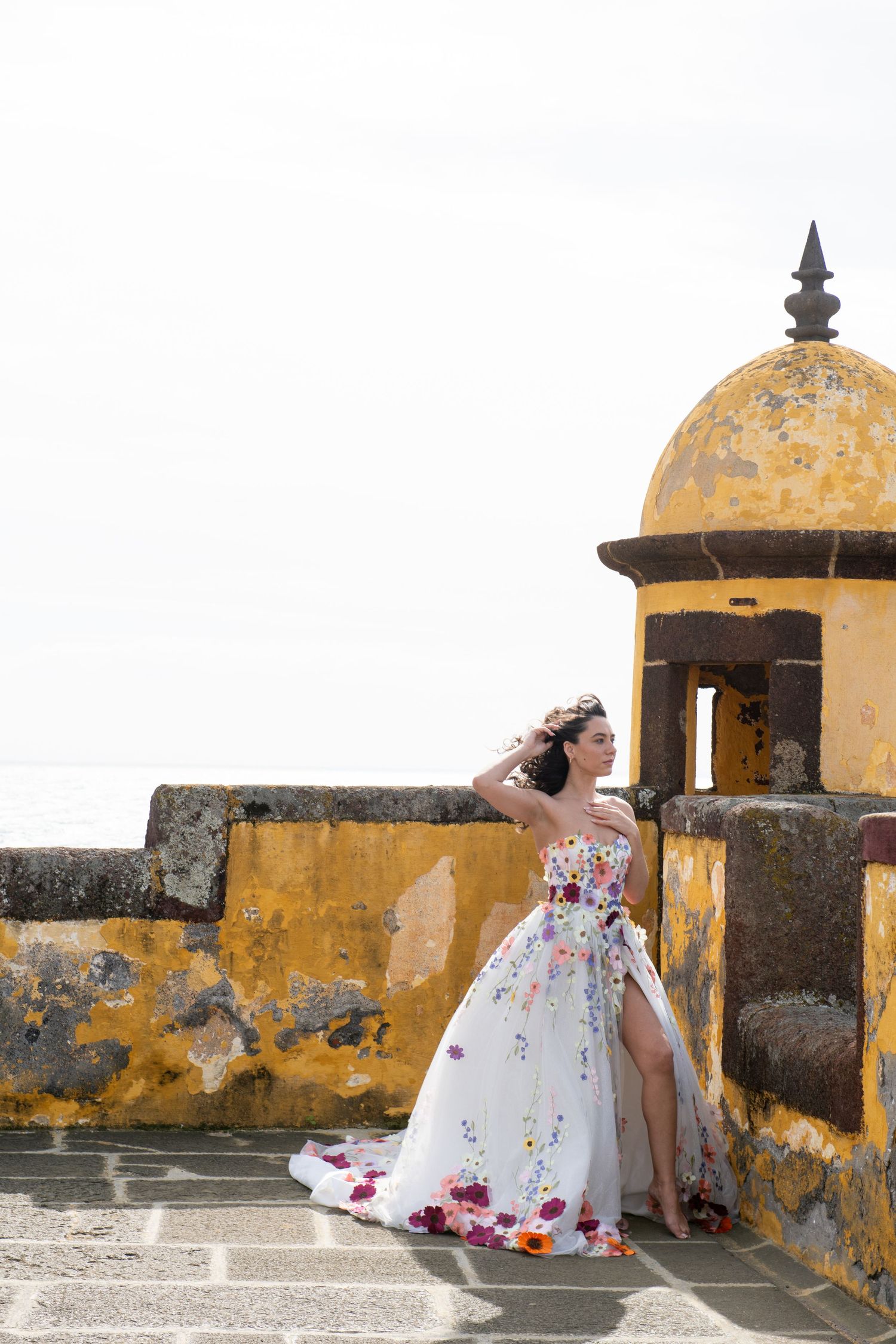 White wedding dress contrasts against yellow walls of historic fortress architecture.
