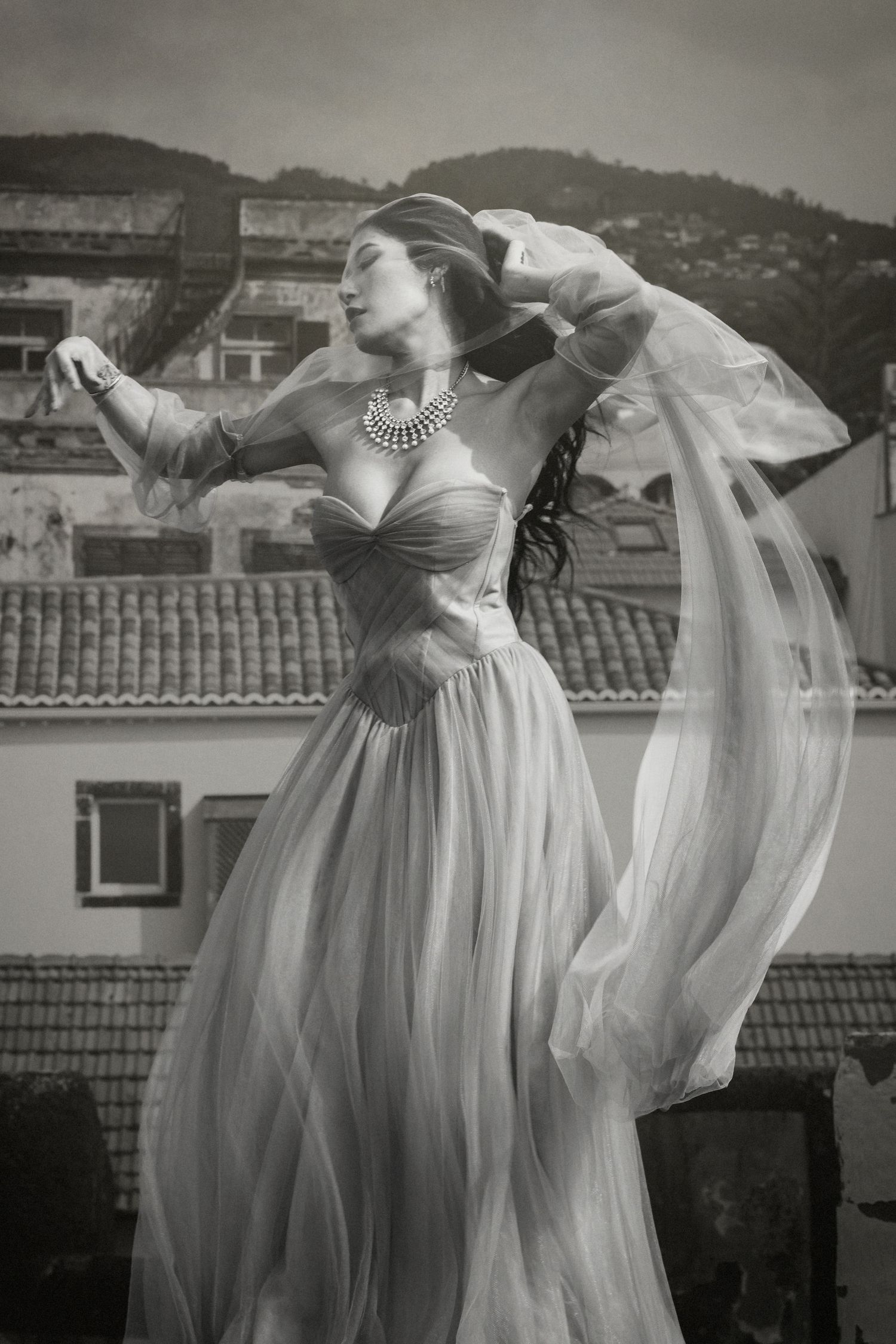 A vintage-style portrait featuring a flowing dress and statement necklace in an outdoor setting.