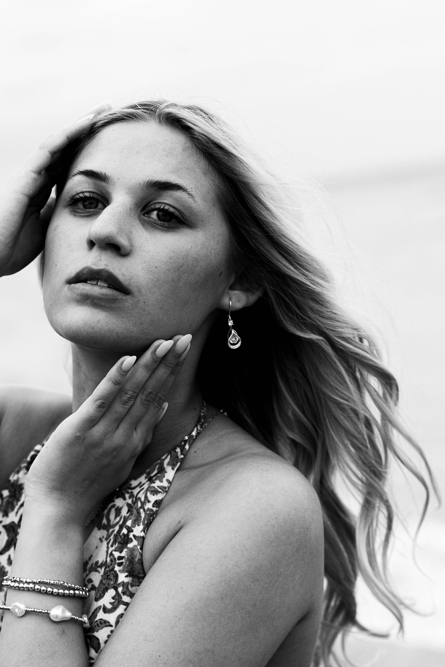 Black and white artistic portrait series featuring dramatic poses with jewelry and wind-swept hair.