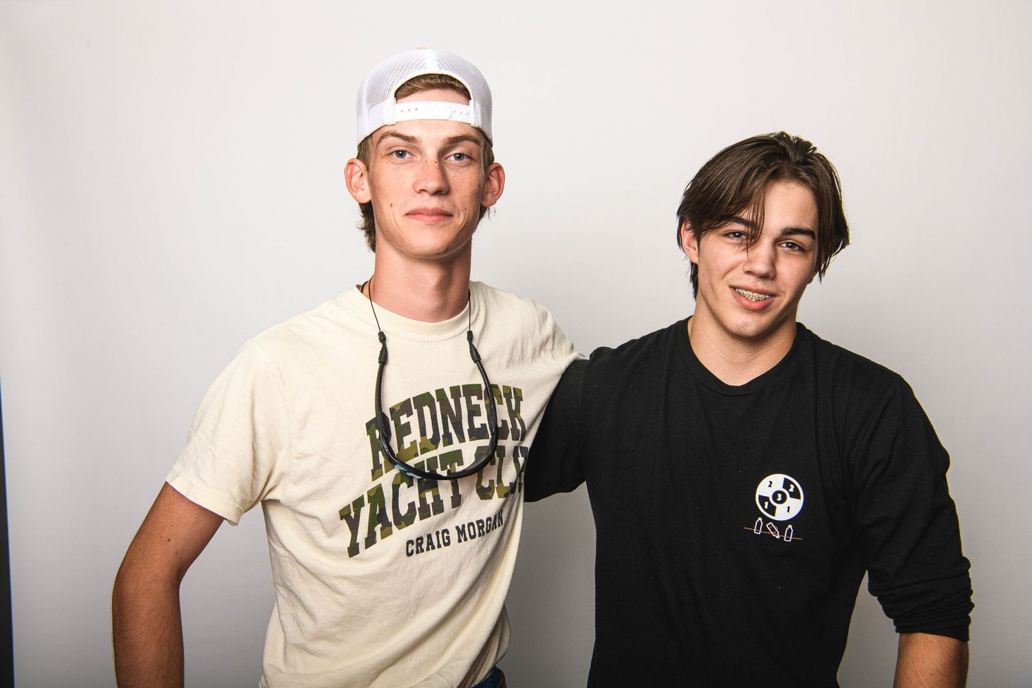 Casual studio shot of two friends in casual wear against white background.