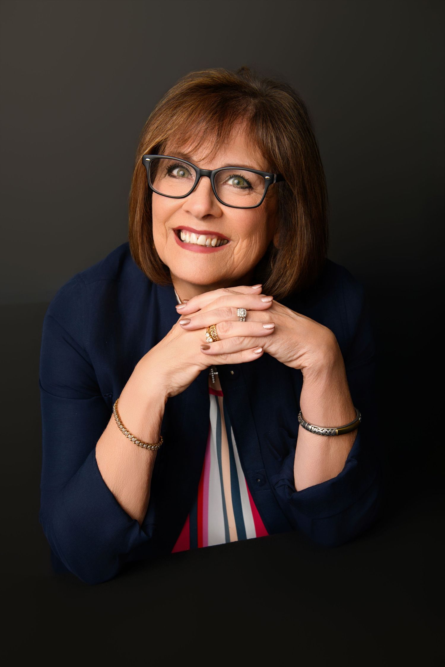 Creative portrait series in navy blazer against dark background showing engaging expressions.