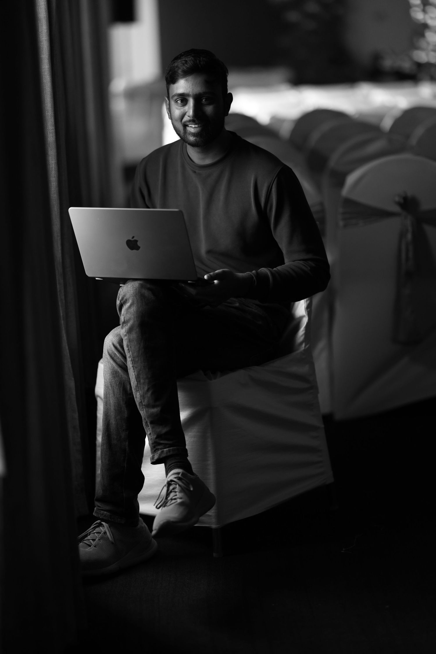 Low-key monochrome image of people working on laptops in a dark room.