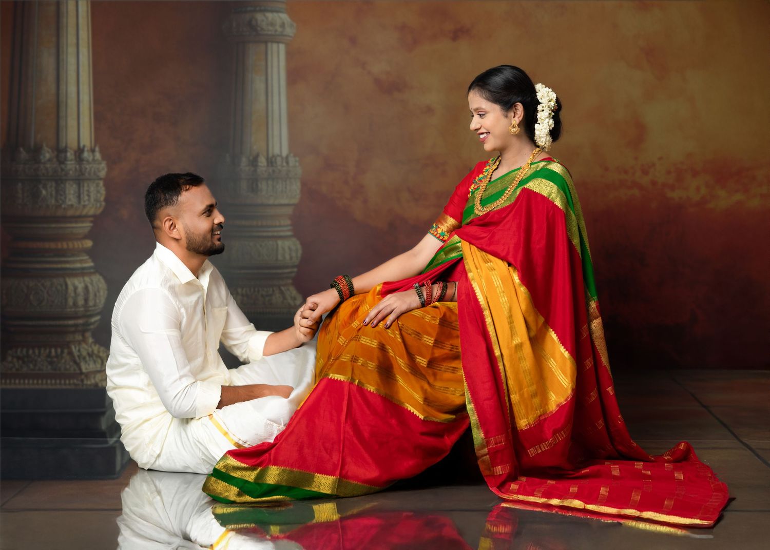 Traditional Indian wedding photoshoot in a temple with vibrant red and gold attire.