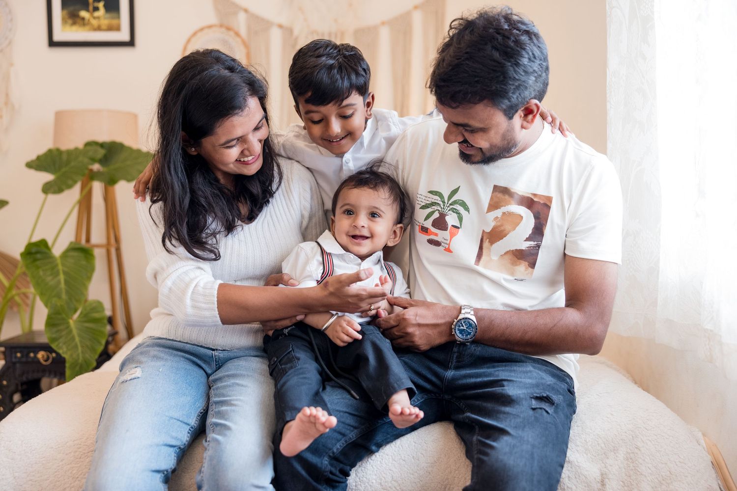 Young family sitting together on couch at home playing and spending quality time together.