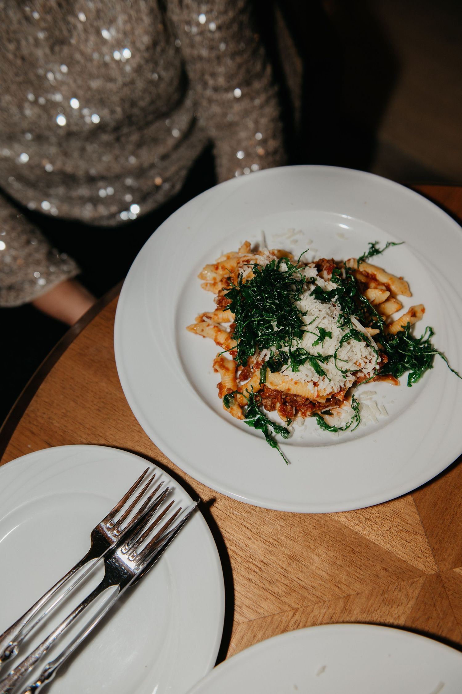 Elegant pasta dish topped with fresh herbs and cheese on a white plate, served at a fine dining restaurant.