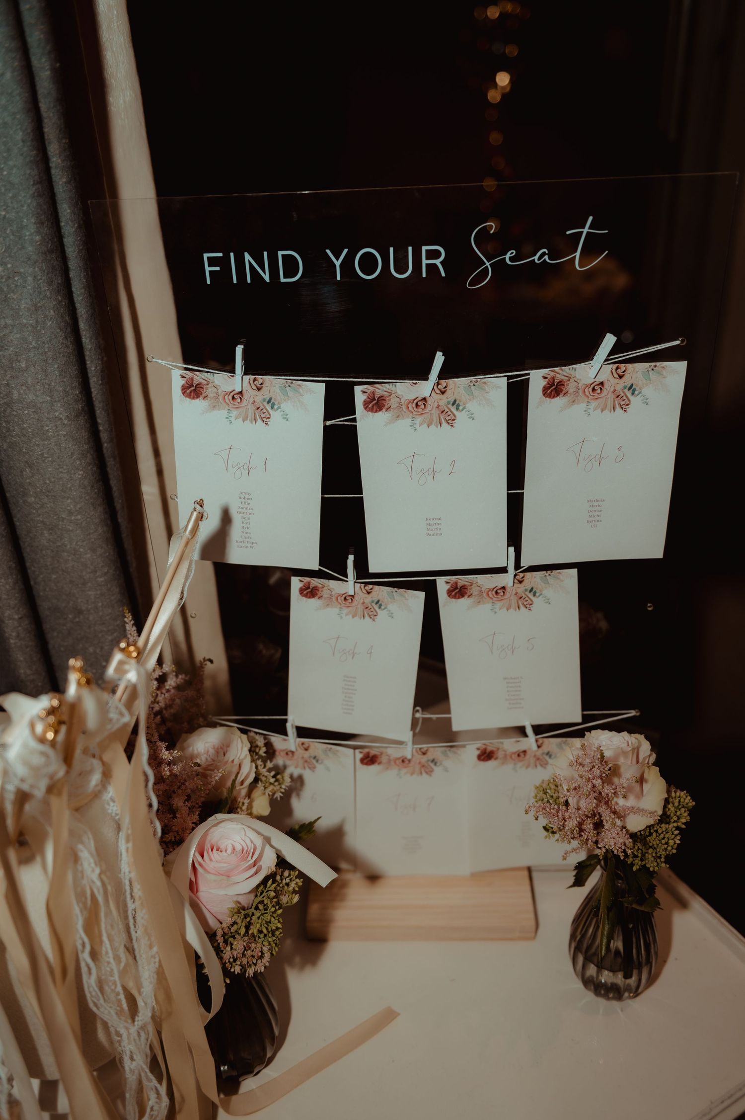 Elegant wedding seating chart display with floral cards clipped to string under a Find Your Seat sign.