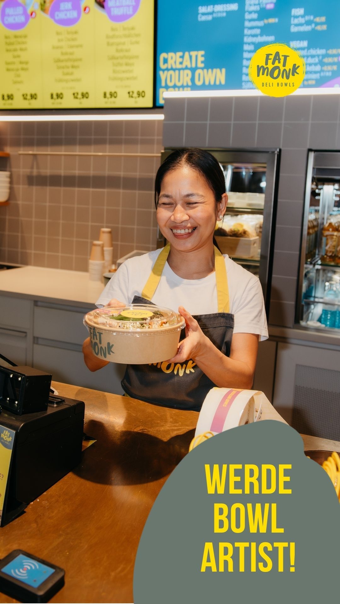 Smiling Fat Monk employee holds a fresh rice bowl at the counter, wearing a yellow apron with a 'Werde Bowl Artist' promotional sign.
