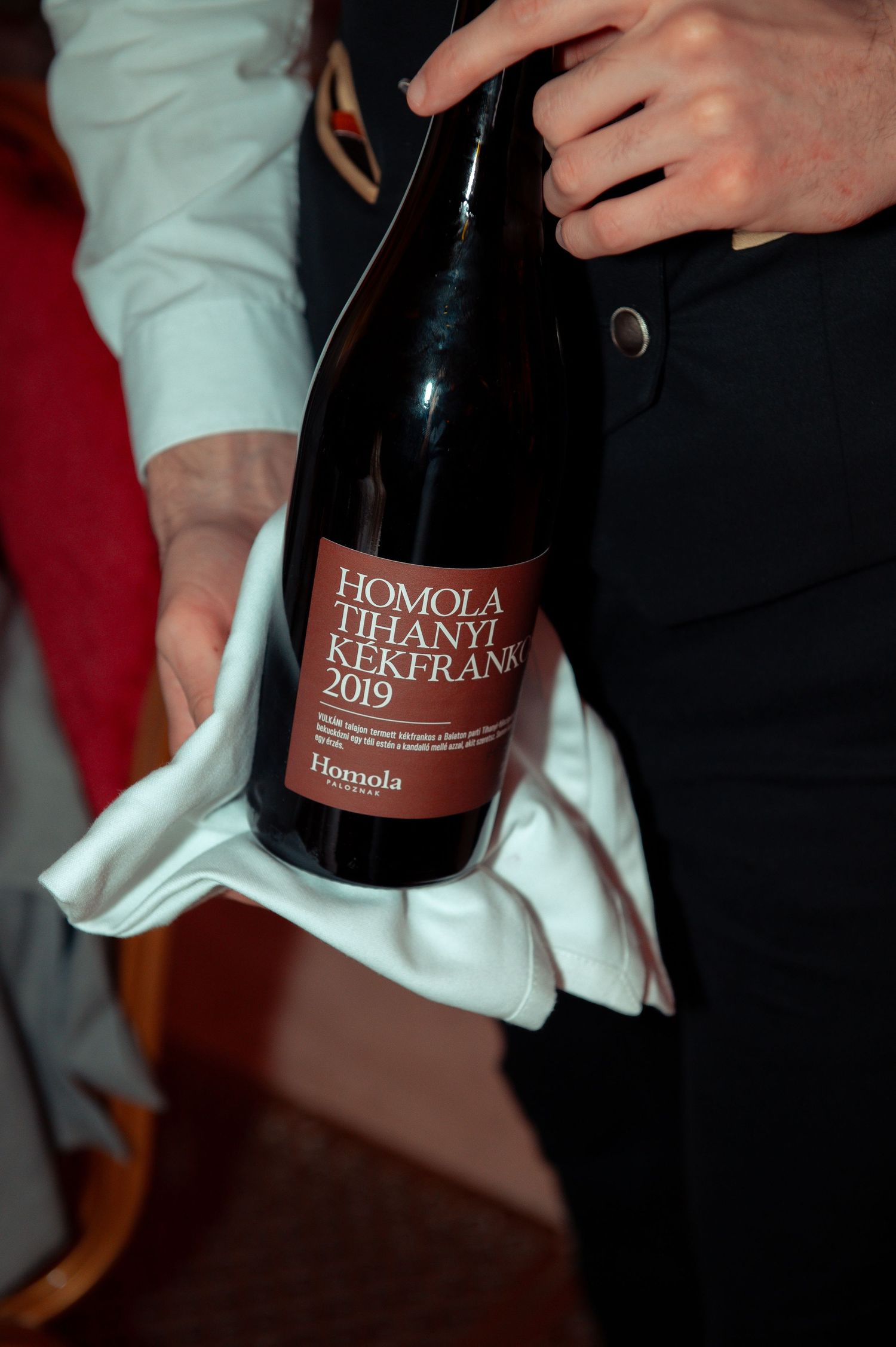 Homola Tihanyi Kékfrankos 2019 red wine bottle held with white cloth by sommelier.